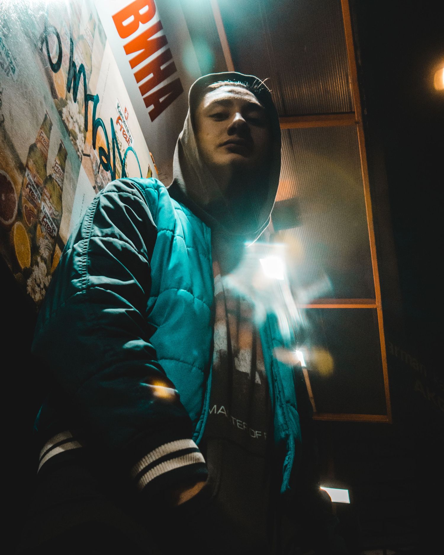 Urban low-angle portrait of a man in hooded jacket with dramatic lighting – street portrait photography in Bulgaria.