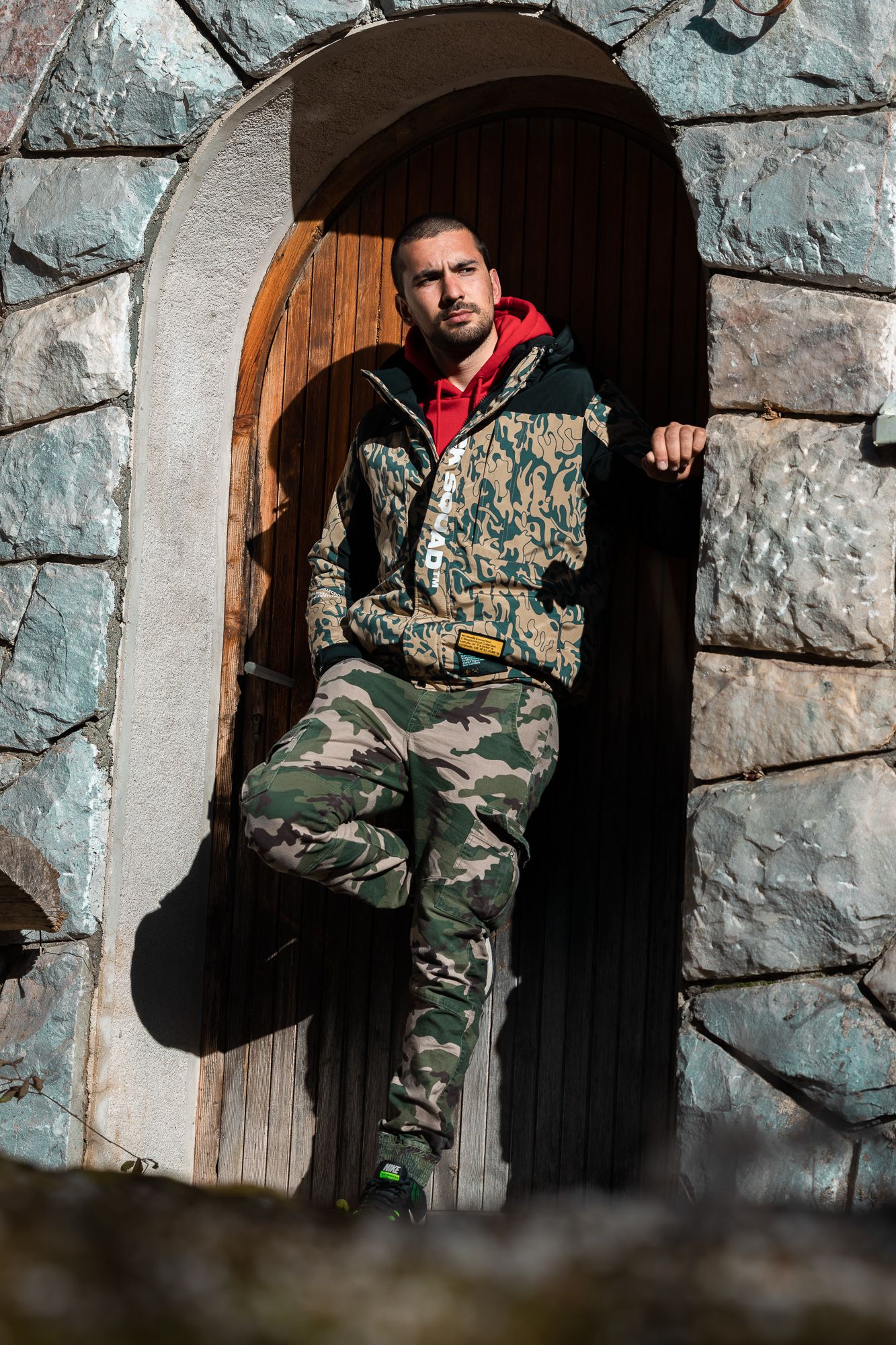 Man standing in stone arch doorway with dramatic natural light – portrait photography in Bulgaria.