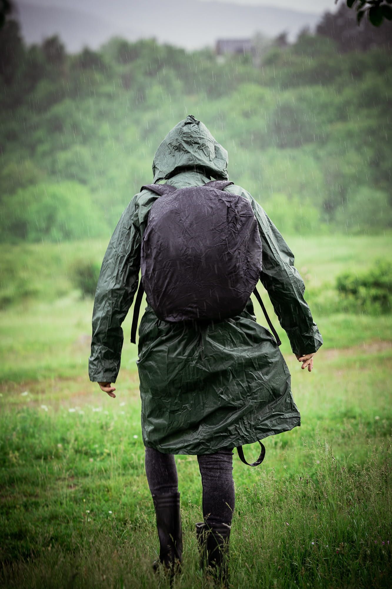 Moody lifestyle portrait of a person walking through green field in light rain – cinematic portrait photography in Bulgaria.