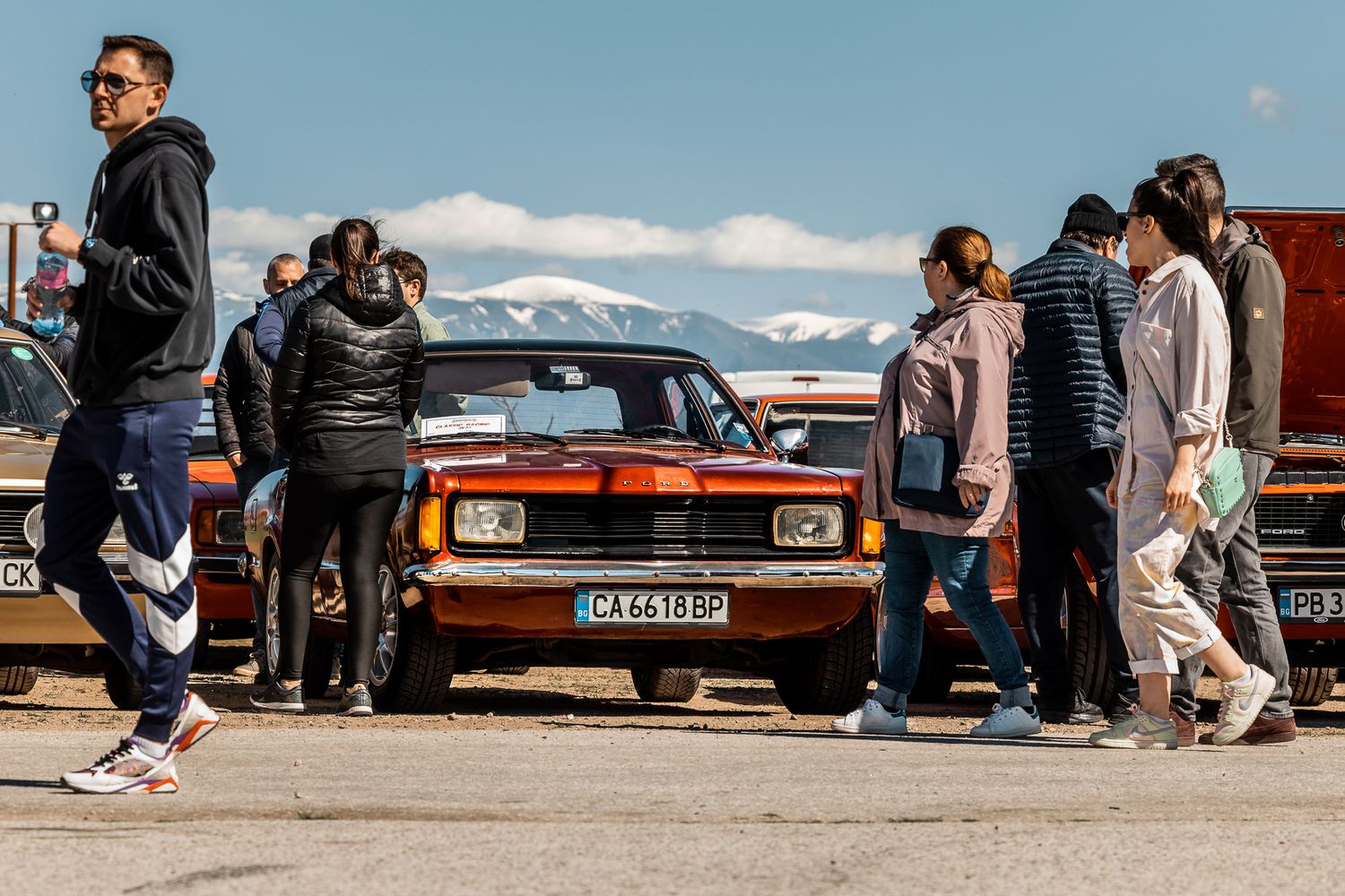 Visitors surrounding a vintage car during a car meet in Bulgaria, highlighting social interaction and automotive culture.