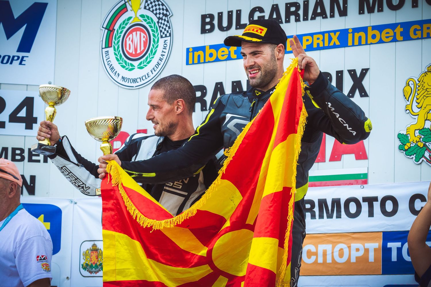 Motorcycle racers celebrating on podium with trophies and national flag – sports photography in Bulgaria.