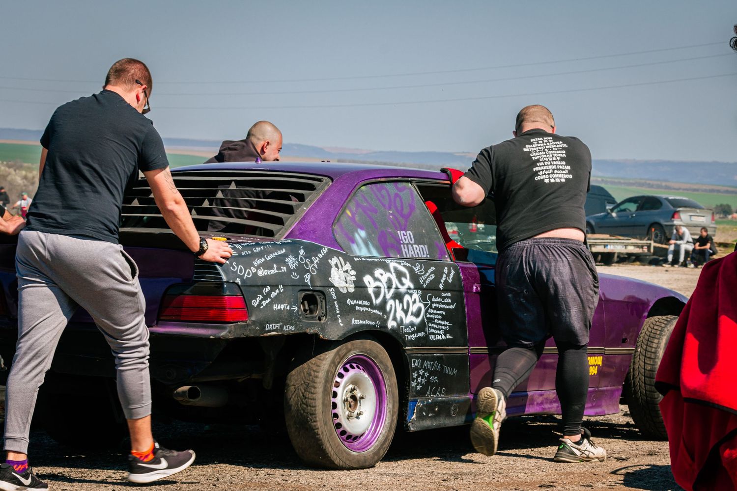Team pushing drift car in paddock area during motorsport event – sports photography in Bulgaria.