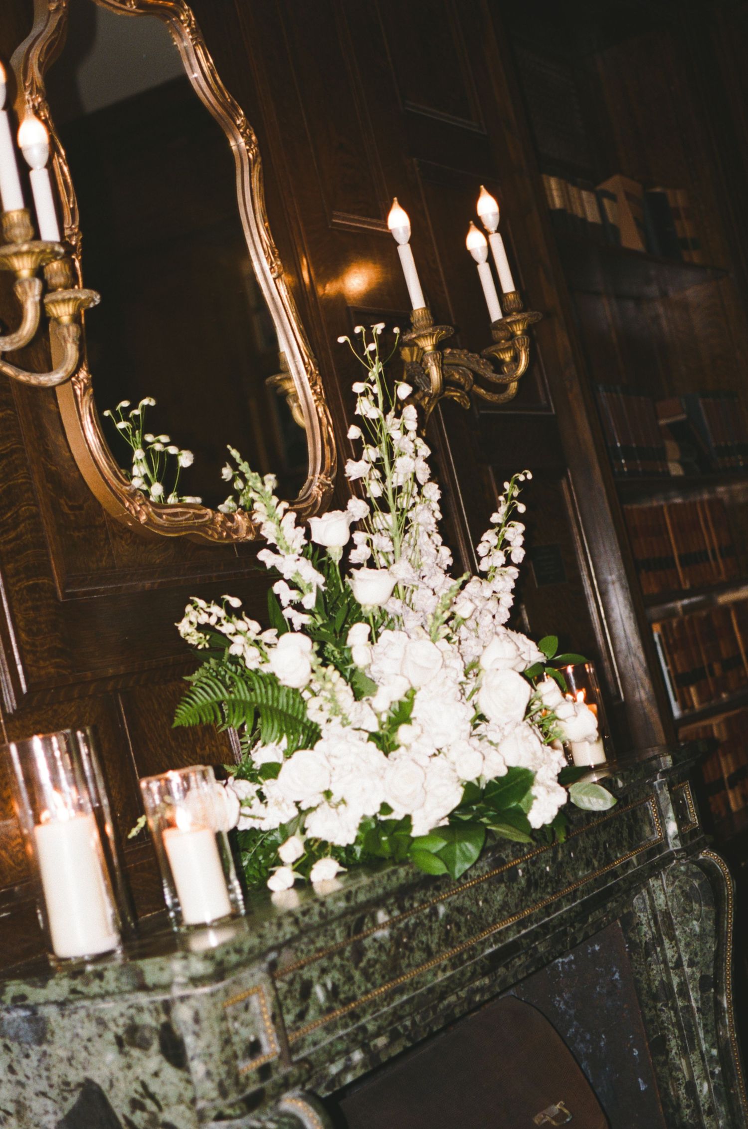 Ornate gold mirrors decorated with white floral arrangements and glowing candles.