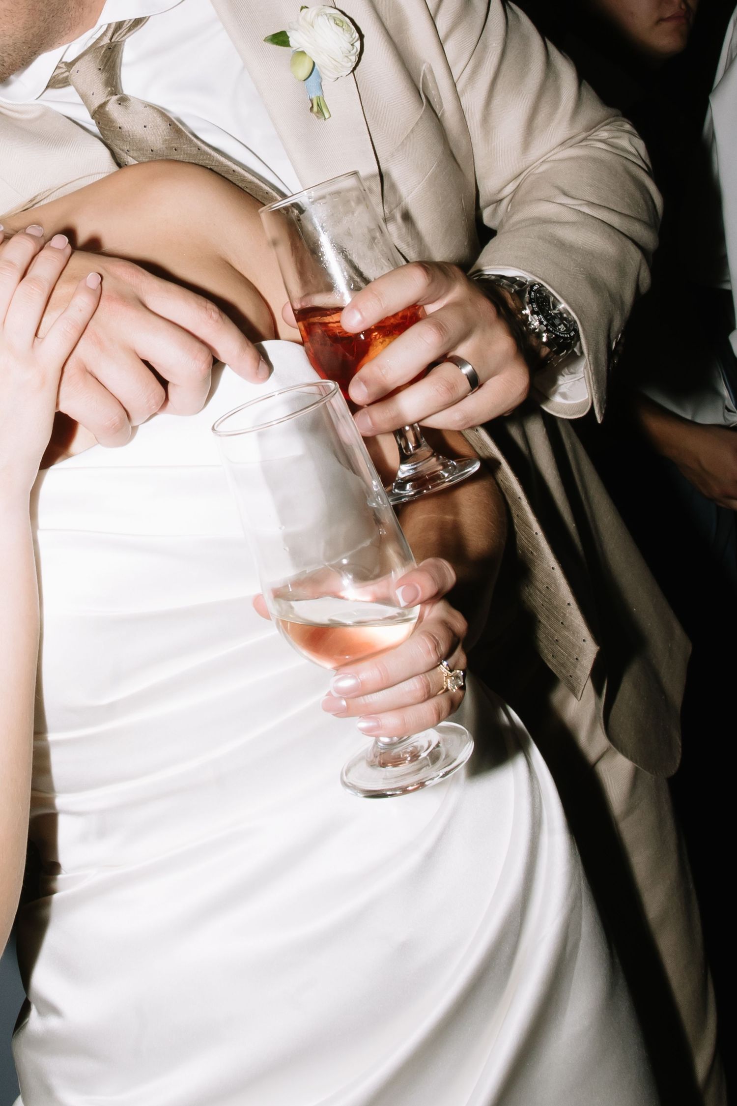 Close-up of hands holding cocktail glasses at a wedding reception.