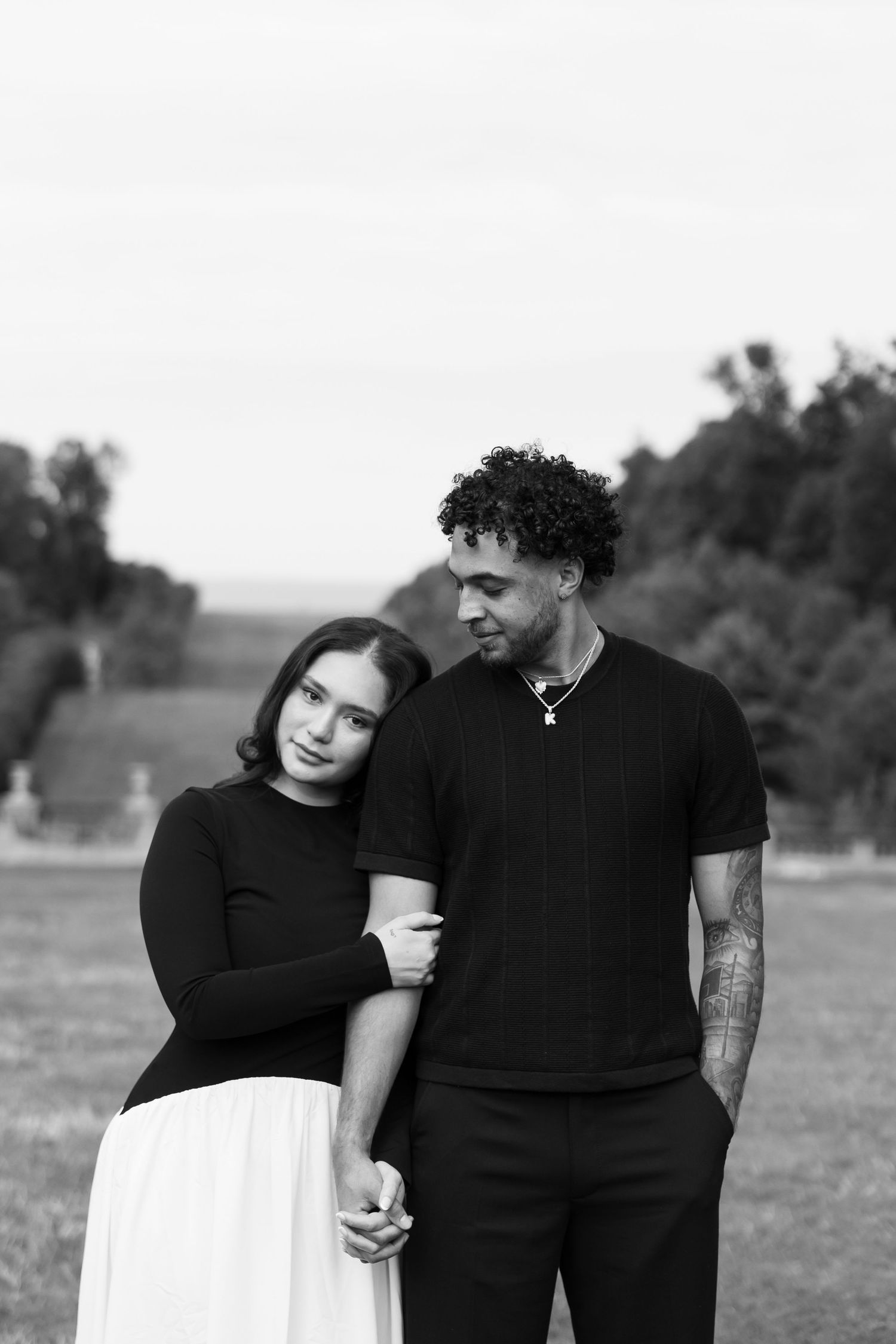 A couple in contrasting black and white outfits standing together outdoors.