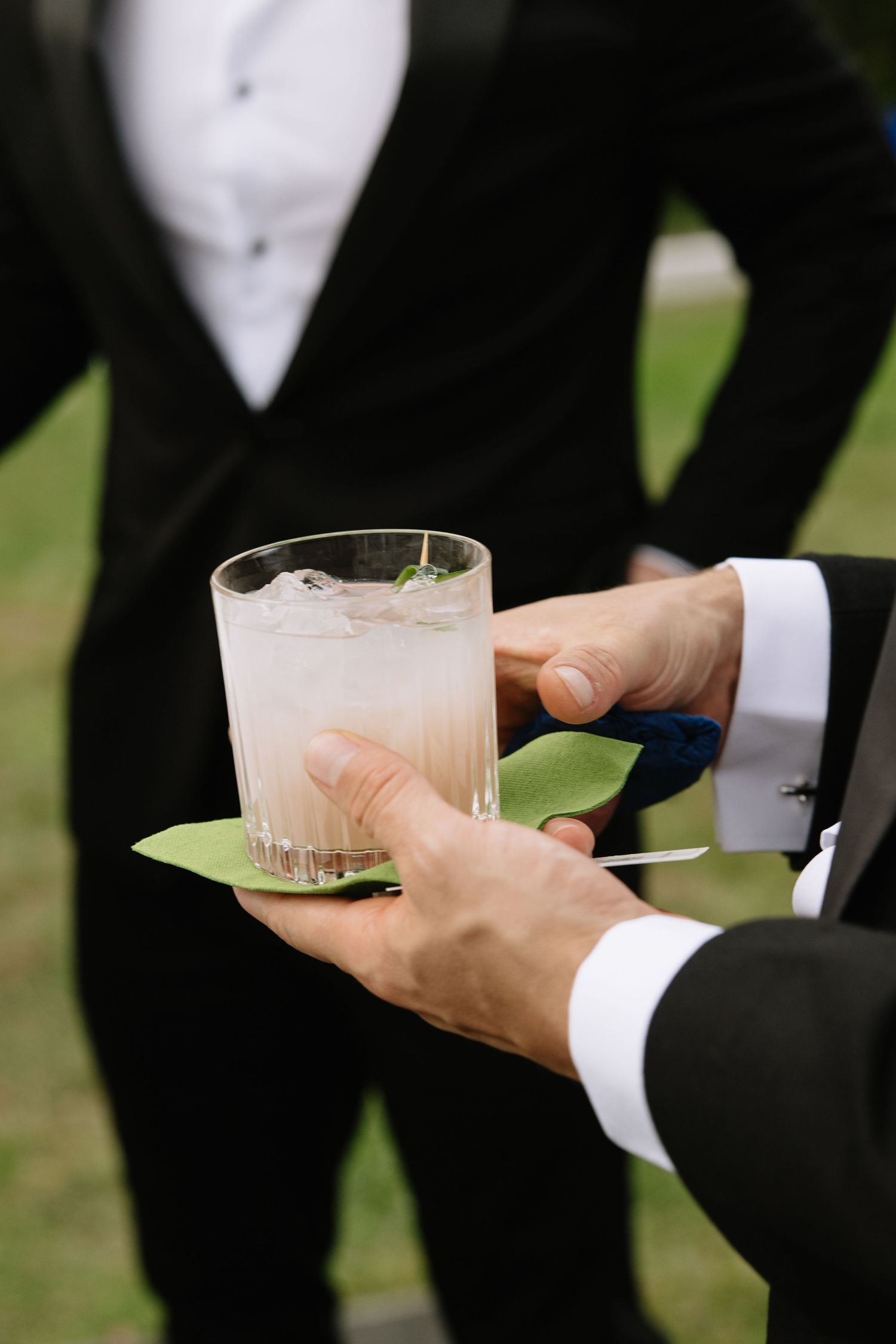Hands in formal attire holding champagne glasses during an outdoor celebration.