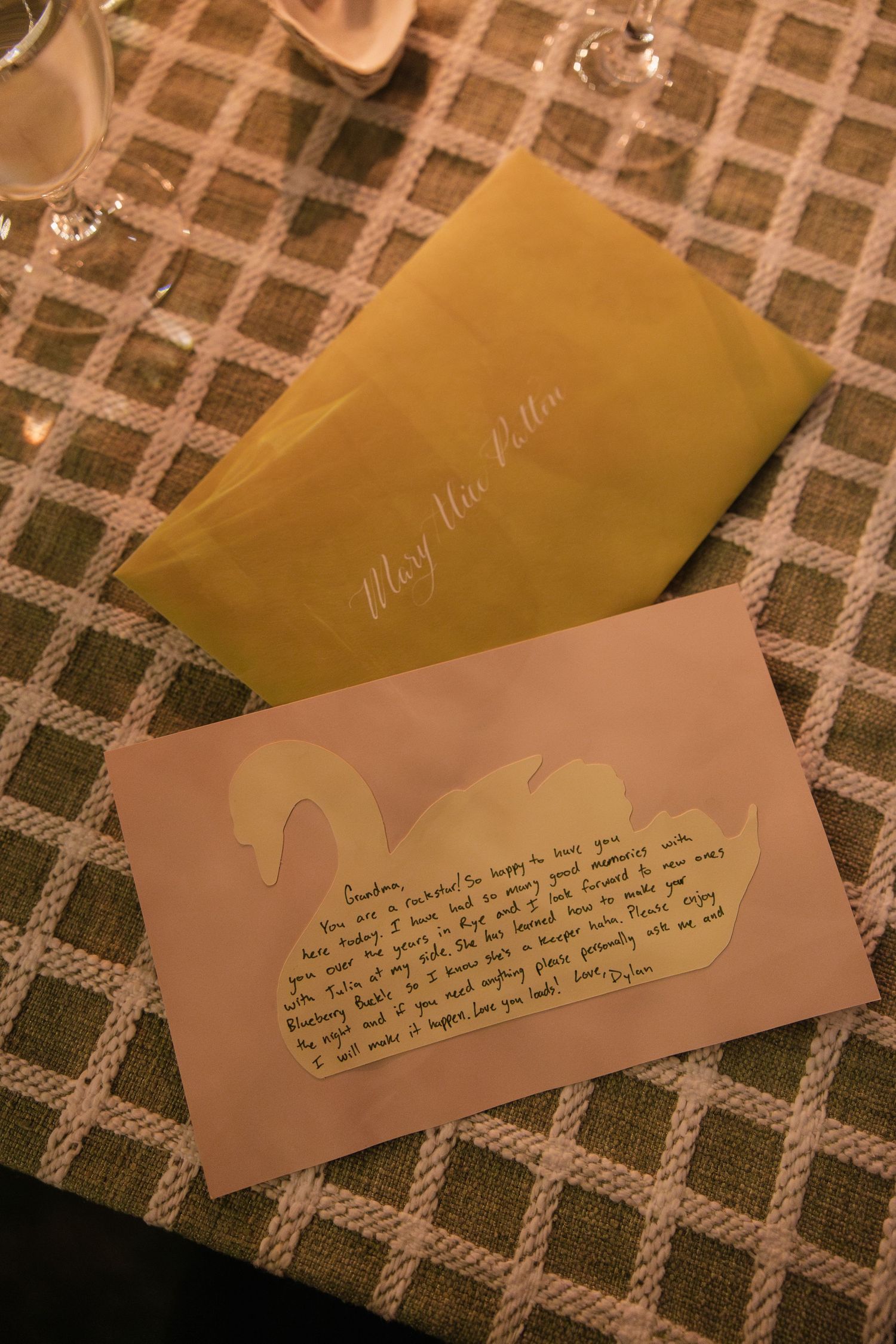 Wedding stationery and handwritten note displayed on patterned tablecloth.