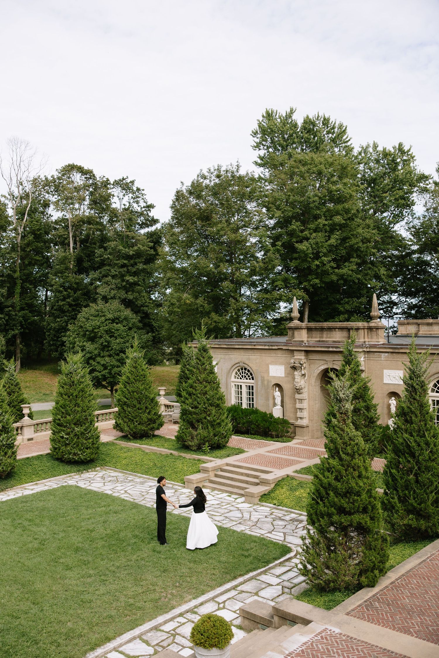 Bride and groom share a romantic first look in a lush garden courtyard of an elegant estate venue.