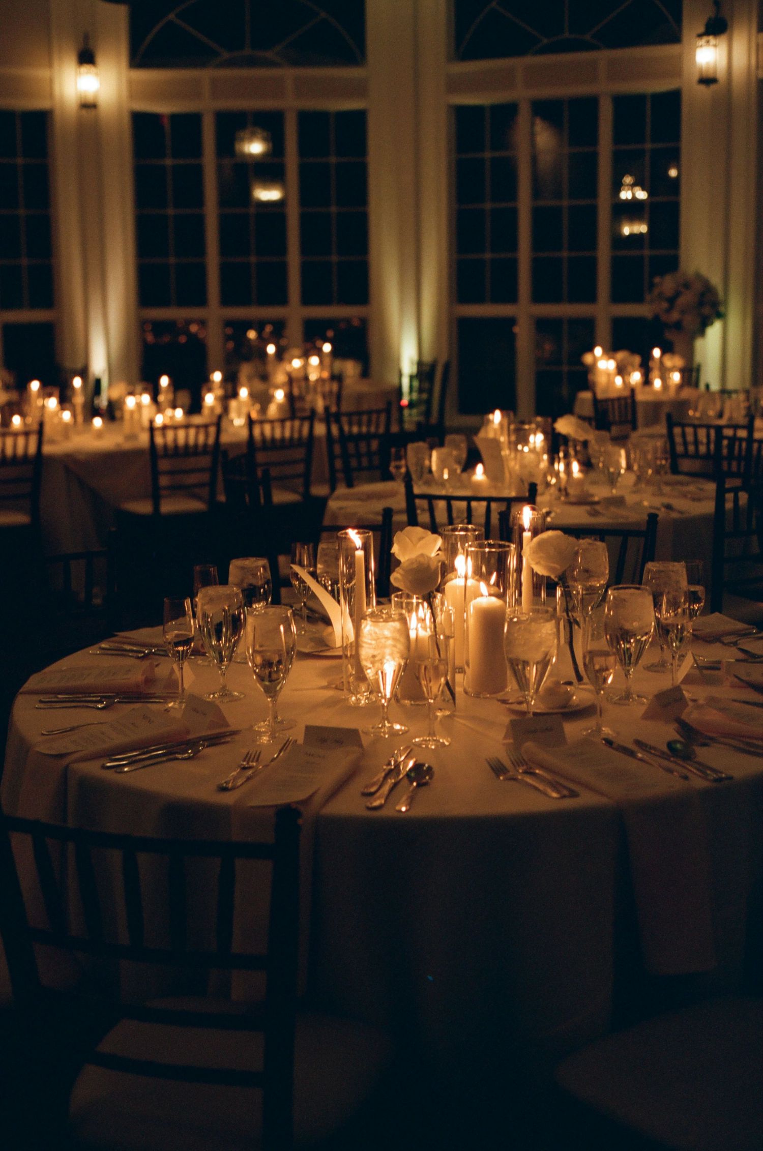 Candlelit round tables set for an elegant evening reception with glowing ambiance.