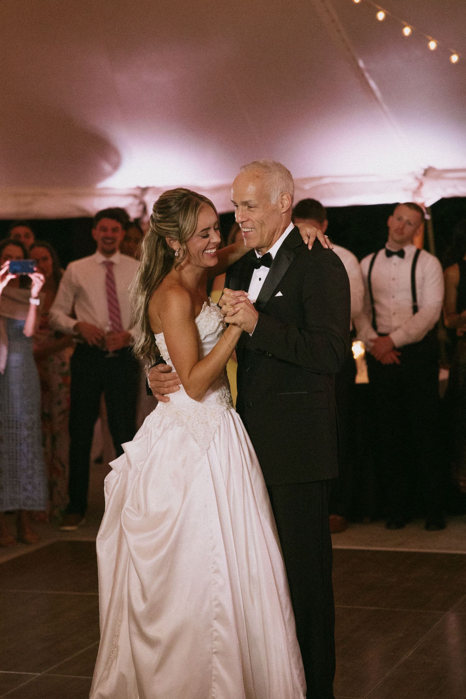 Couples dancing at an evening wedding reception under string lights.