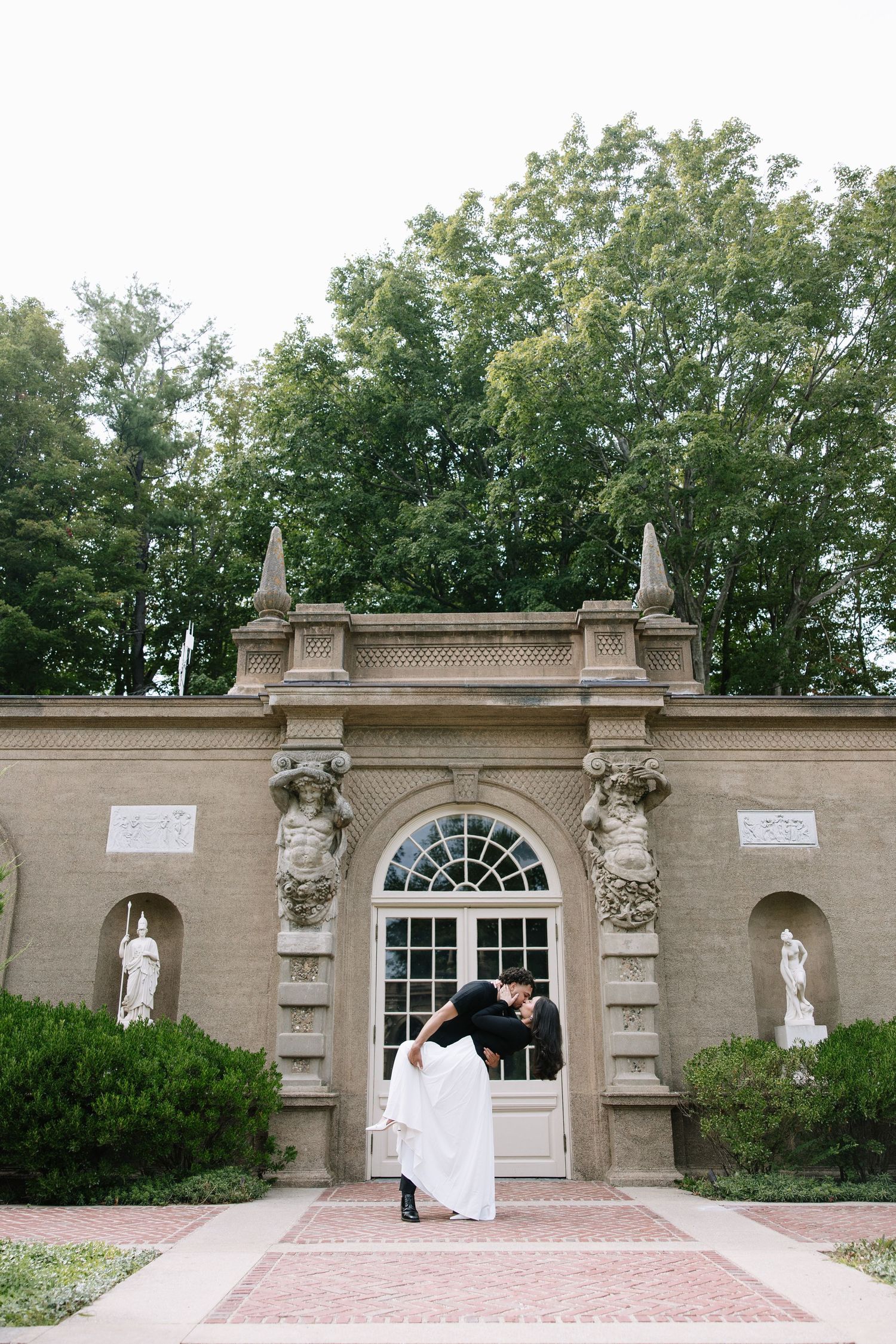 Wedding photoshoot at an elegant stone archway with classical architectural details.