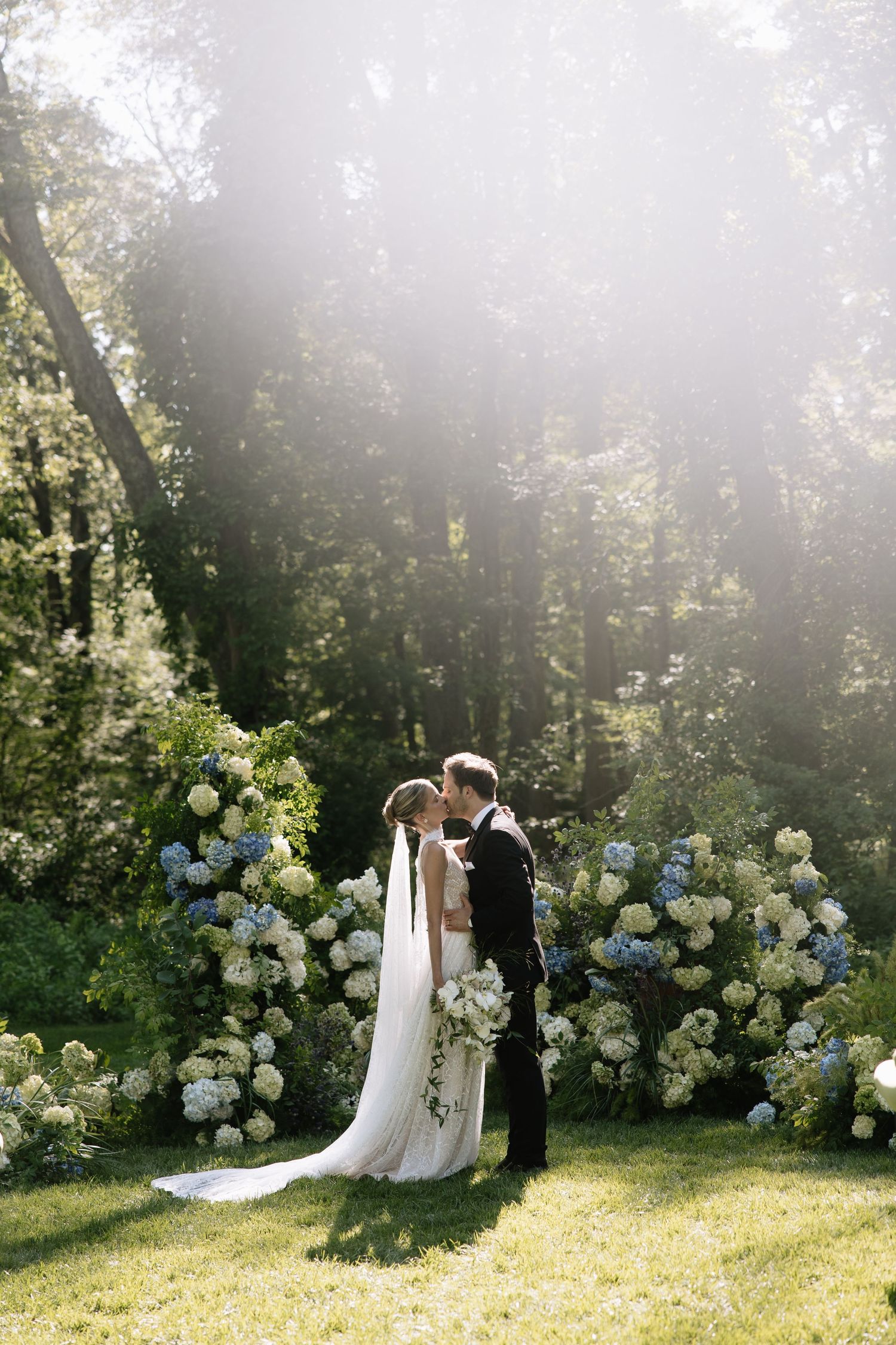 Wedding ceremony setup with lush hydrangea arrangements in a sunlit garden.