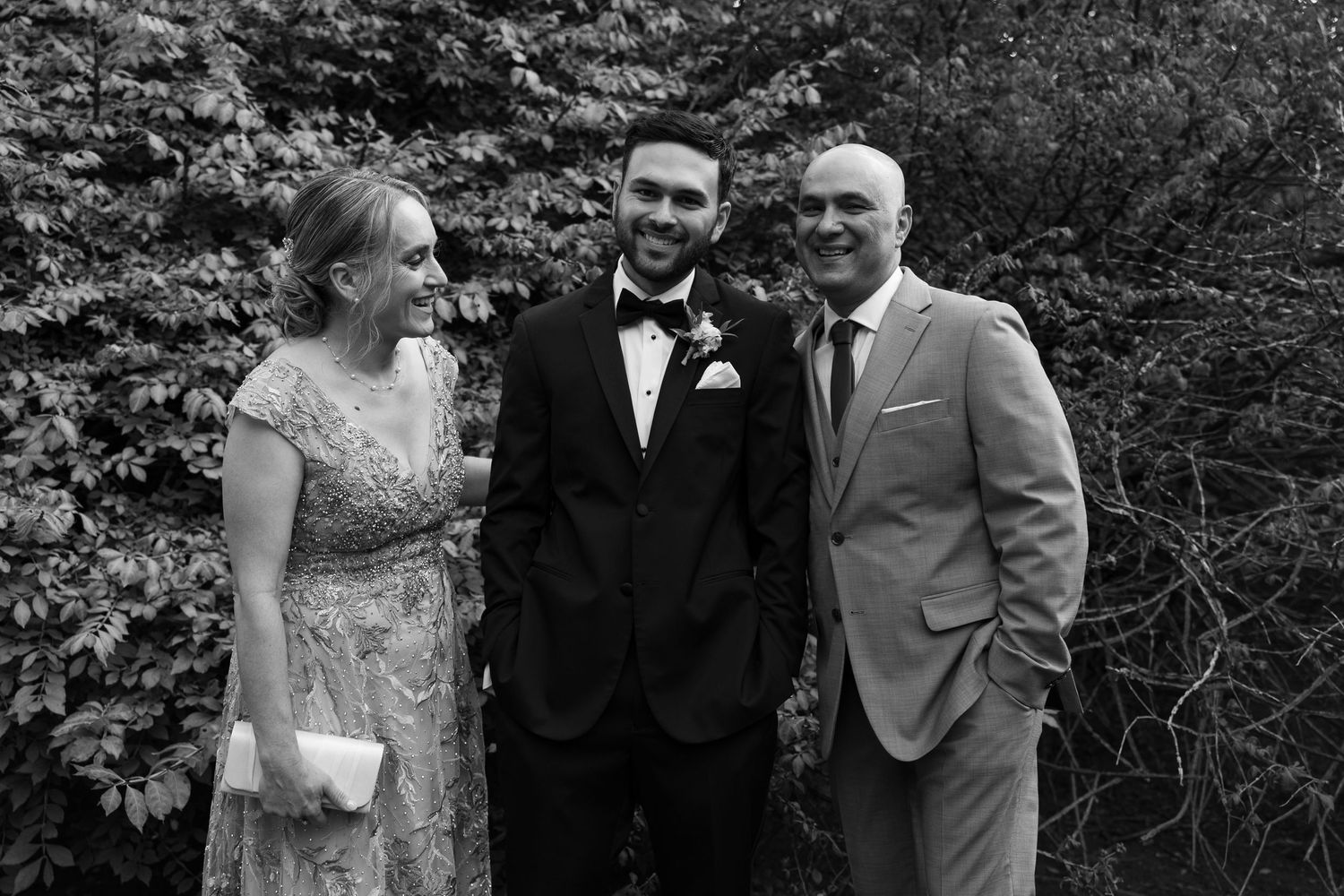 Wedding party members in formal attire posing outdoors in black and white.