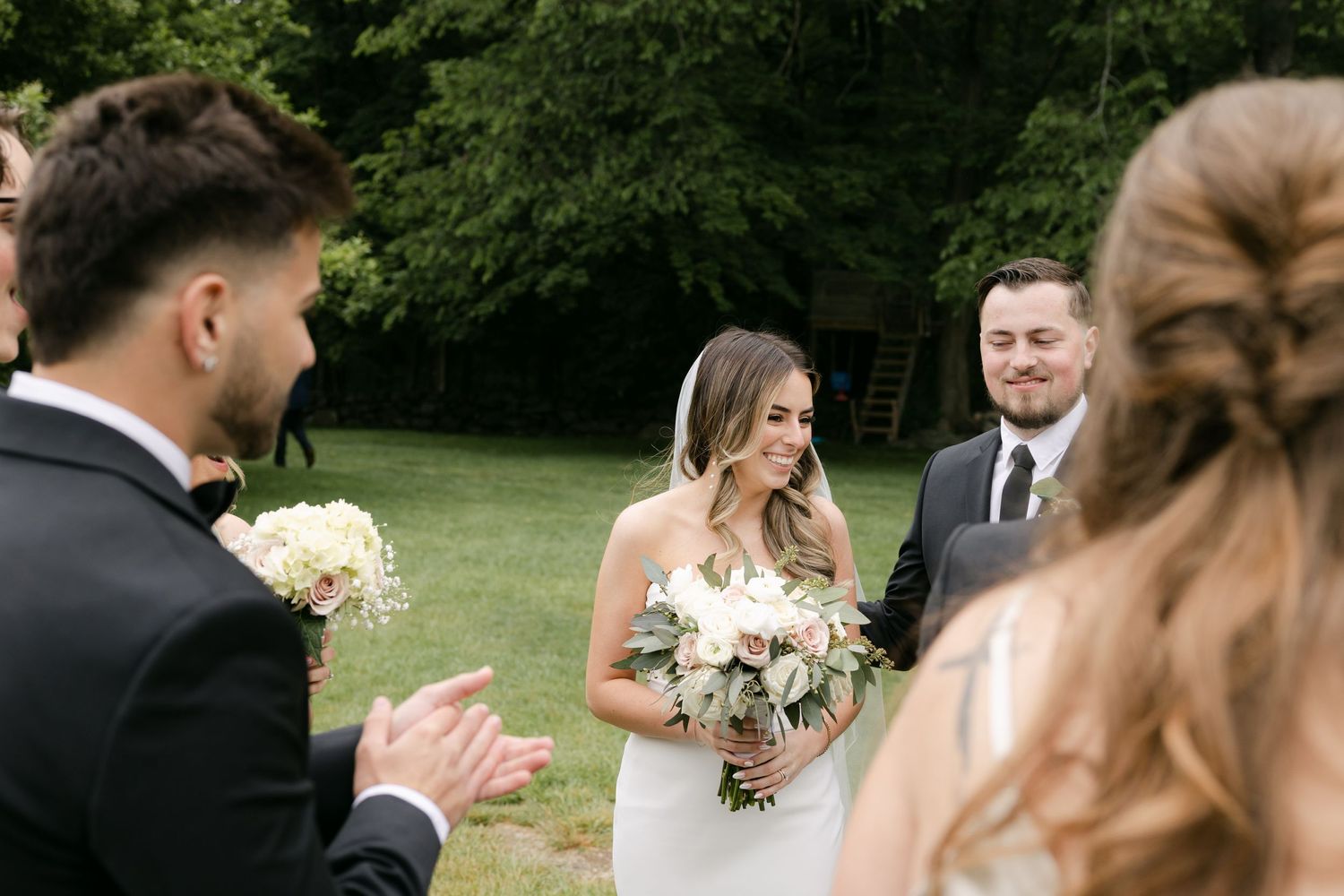 Outdoor wedding ceremony with white floral arrangements and natural greenery.