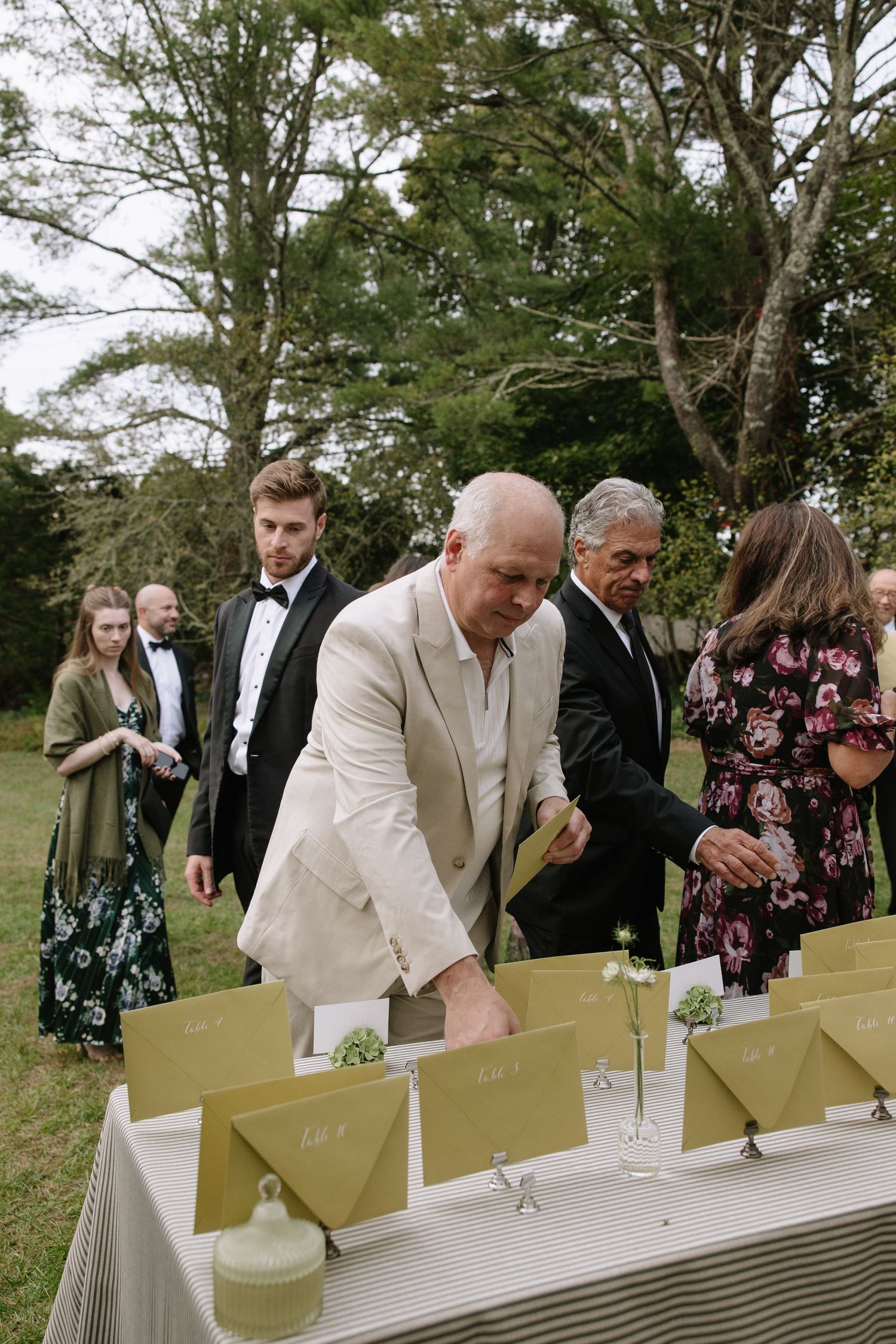 Wedding guests serving themselves drinks at an outdoor bar setup.