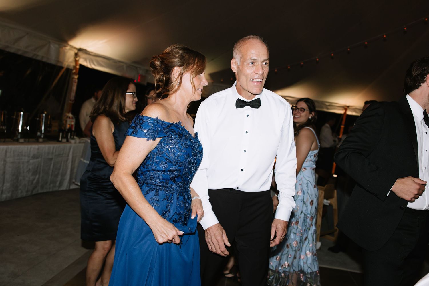 Wedding guests dancing and celebrating at an evening reception.