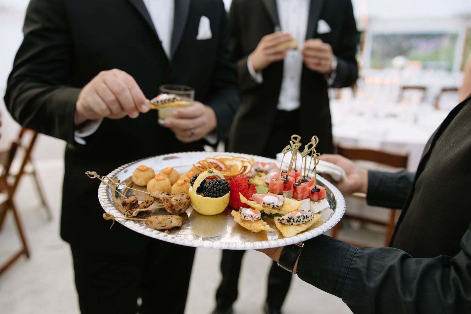 Wedding reception plates filled with appetizers and hors d'oeuvres on elegant place settings.