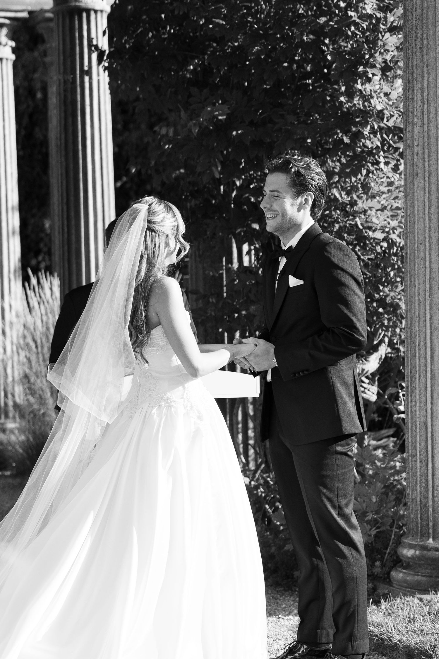 A romantic black and white wedding moment captured between a bride in a flowing gown and groom in a classic tuxedo.