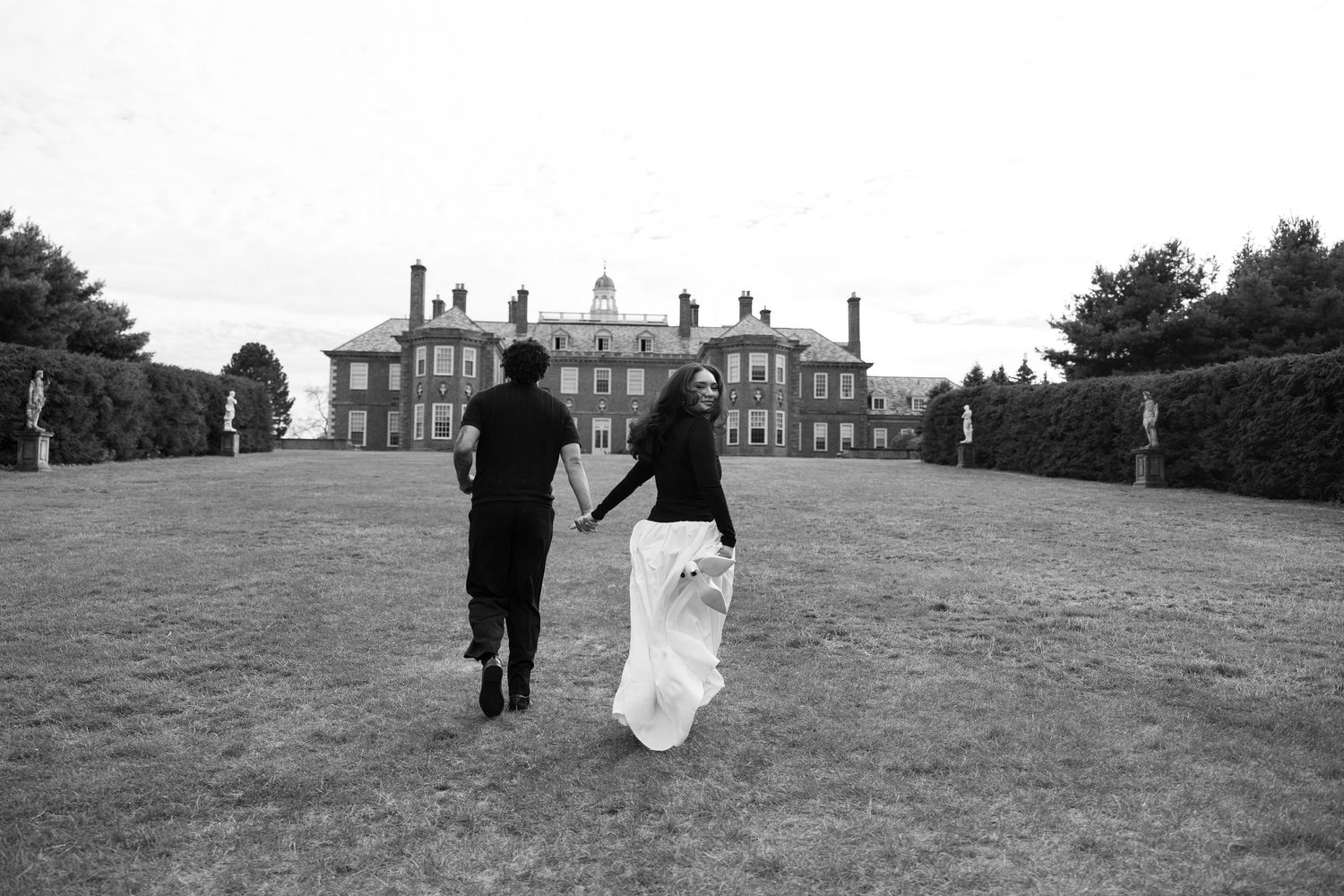 Silhouetted figures walking across a vast lawn towards a historic mansion.
