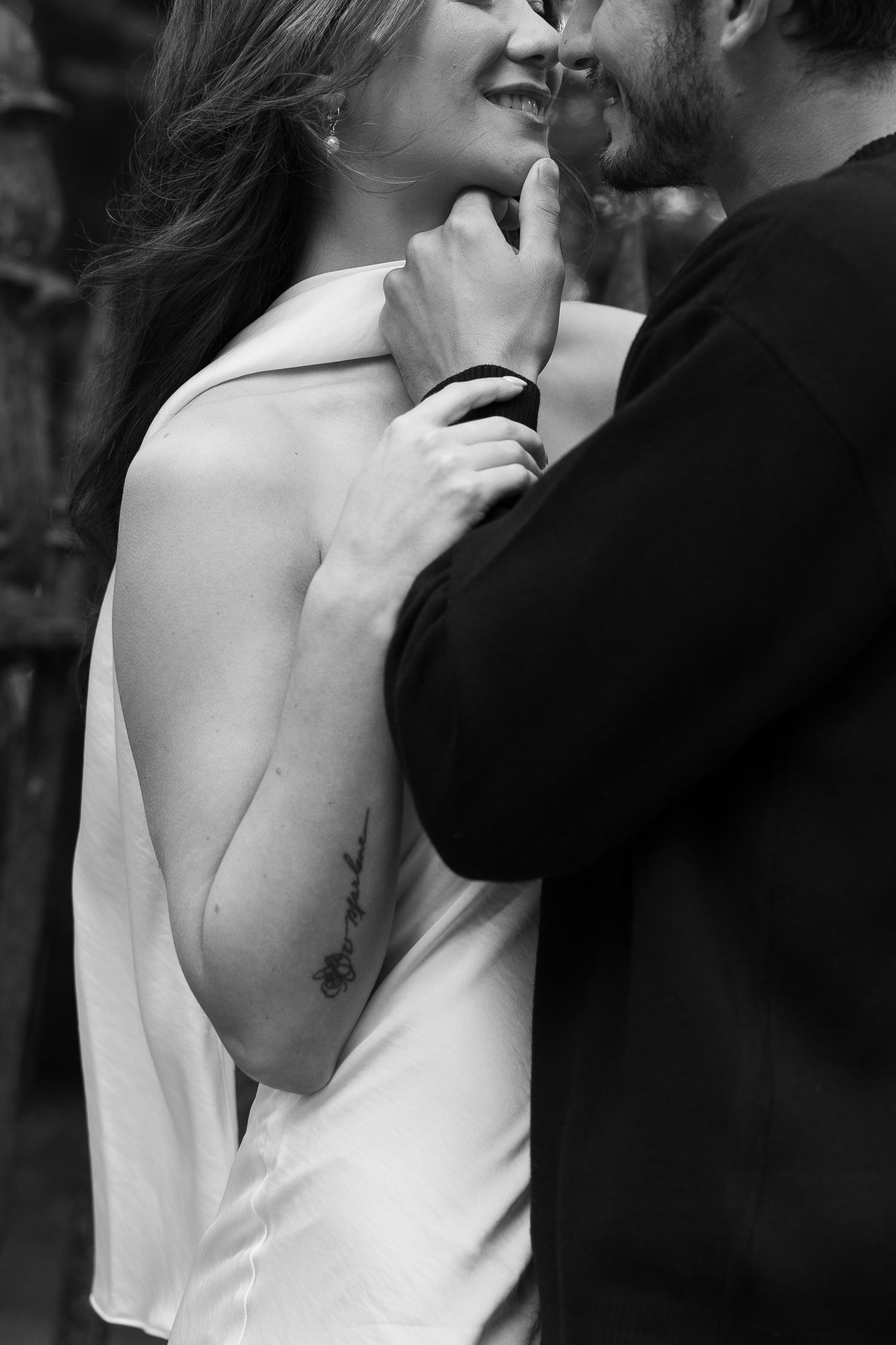 An intimate black and white portrait of a couple in a close embrace.