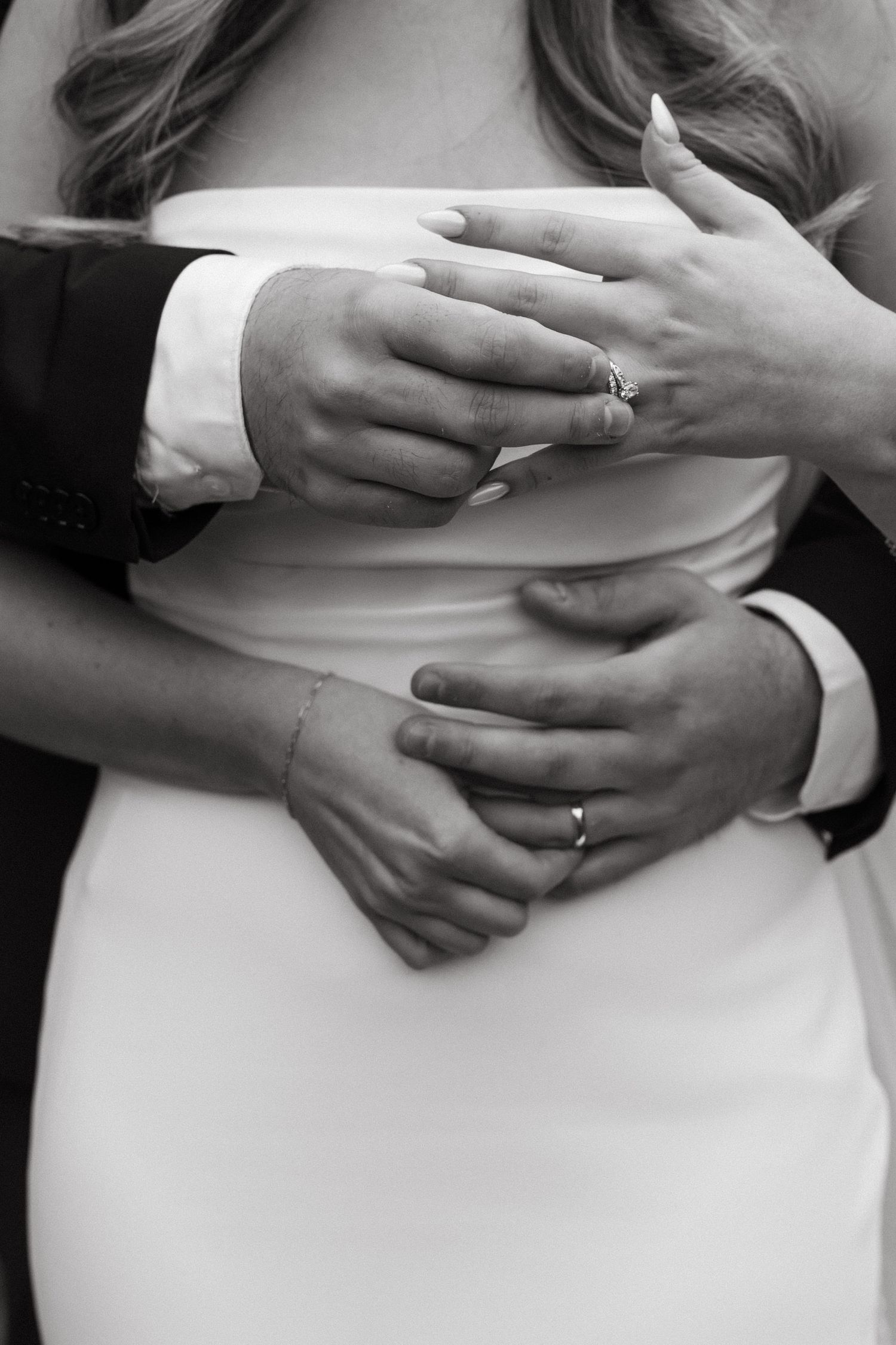Close-up series of hands embracing around a white dress waist, showing wedding rings and tender moments.
