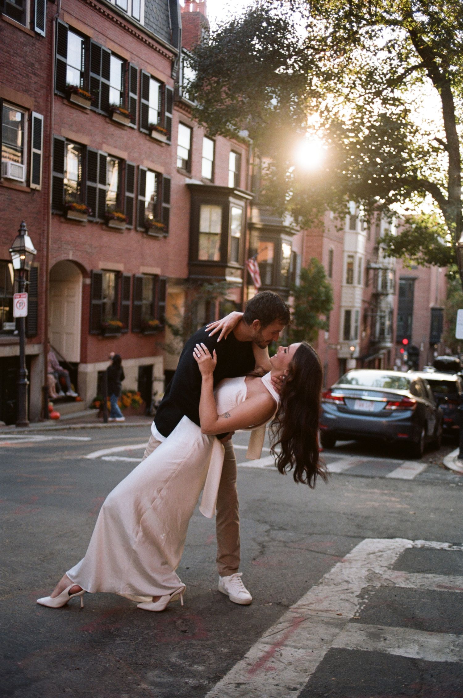 A romantic dip pose on a charming Boston street corner at sunset with brownstone buildings.
