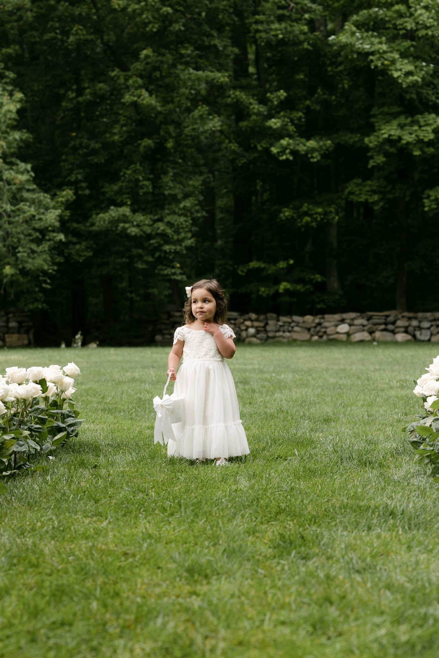 White wedding dress flows across green grass in an outdoor setting.