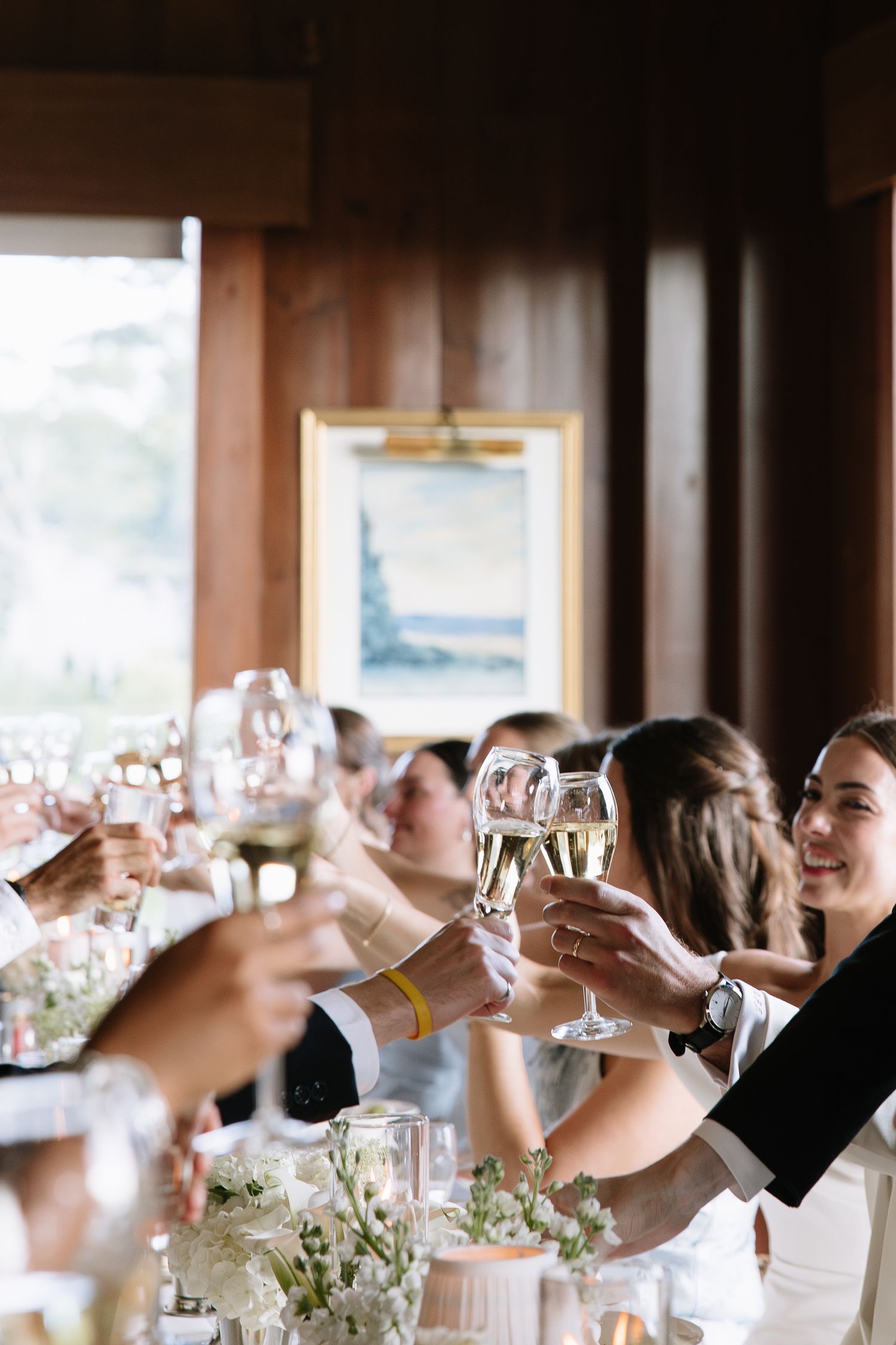 Wedding guests raising champagne glasses in a toast at elegant indoor reception.