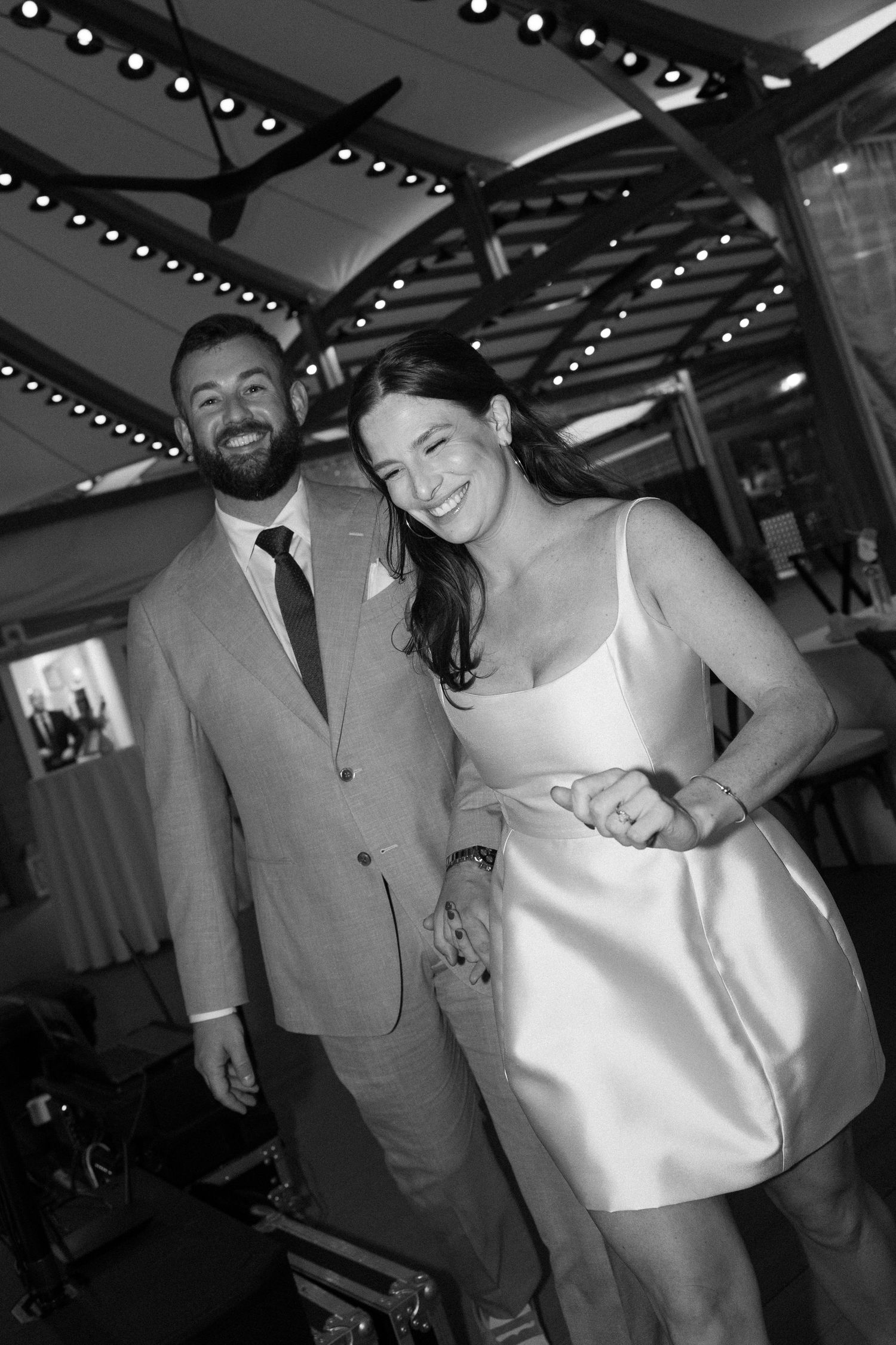 Happy bride and groom smiling together at their wedding reception in black and white photo.