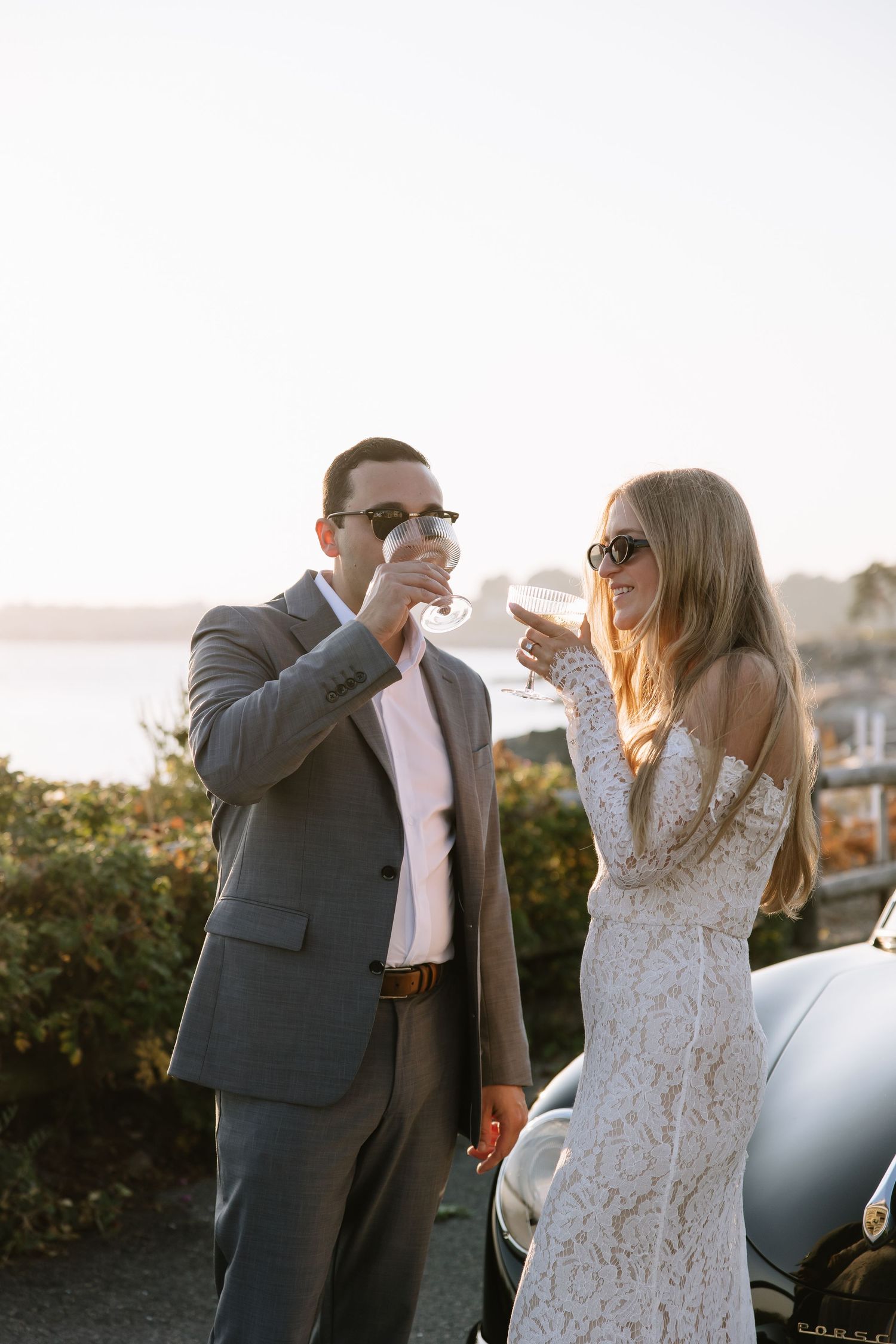 Couple enjoying champagne together at sunset overlooking coastal scenery.