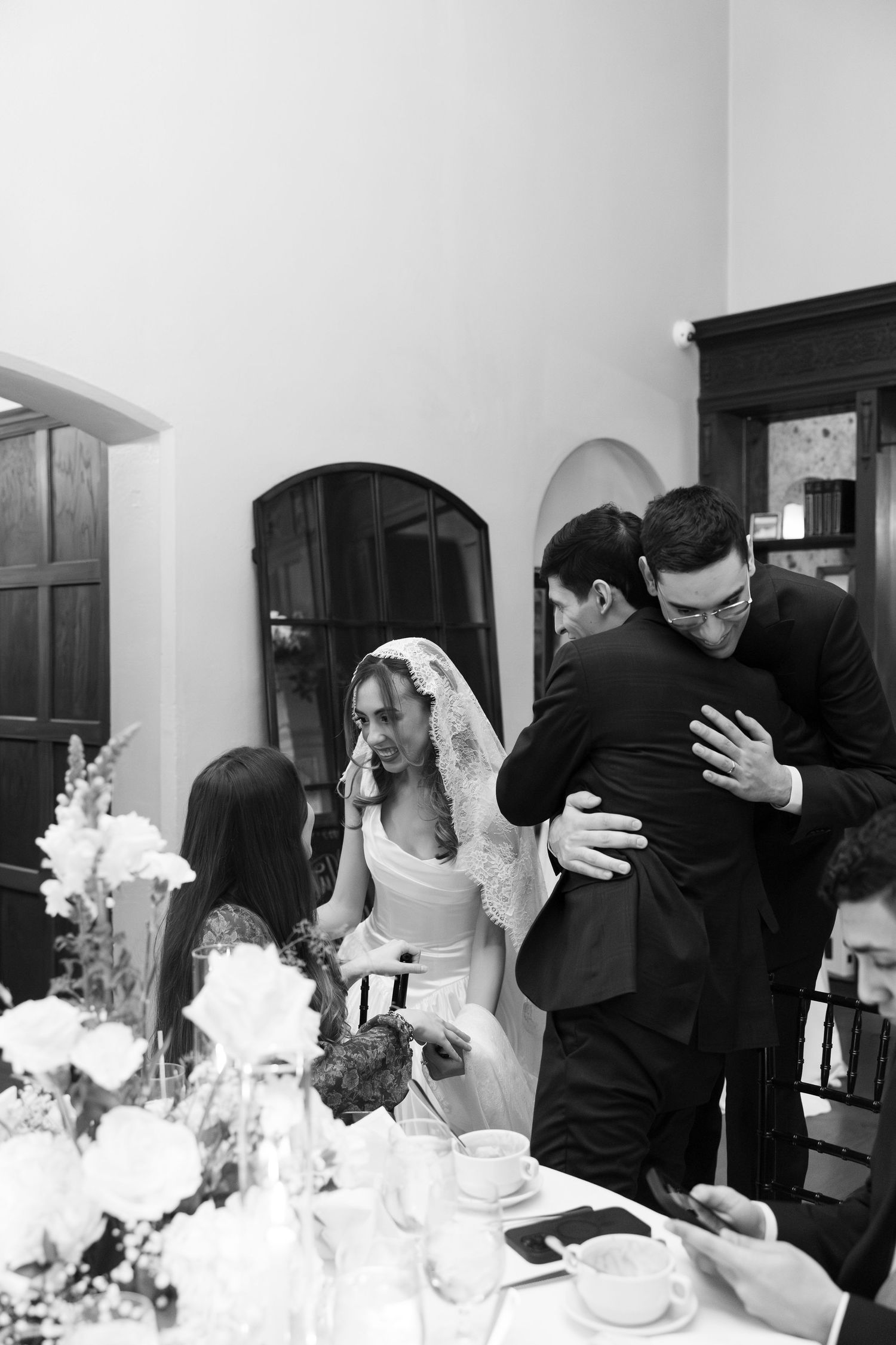 Wedding celebration scene with guests in black and white attire at an indoor reception.