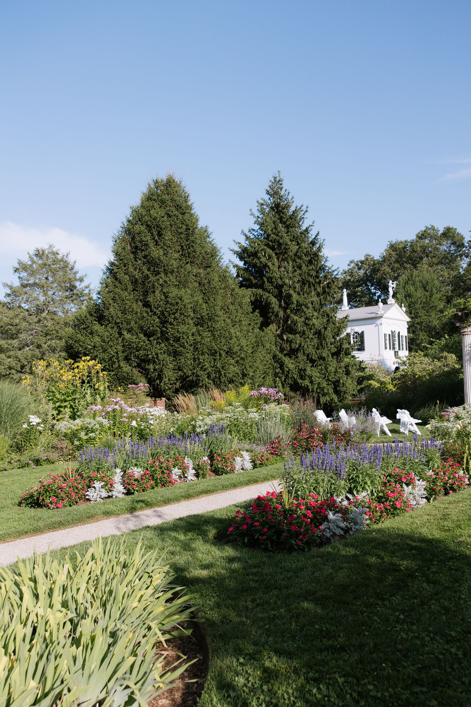Beautiful garden landscape with colorful flowers, walking paths and a white building in the background.