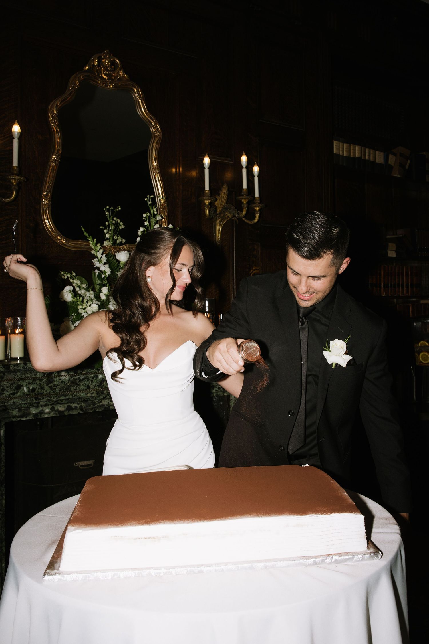 Wedding couple cutting their cake together at an evening reception.