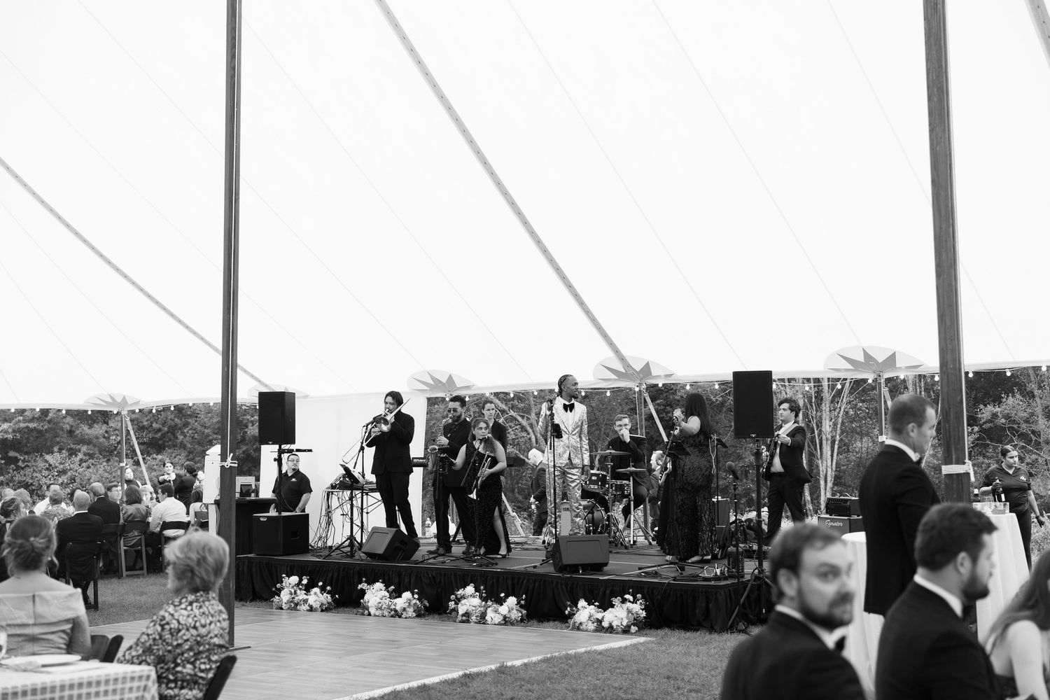 Wedding guests seated under a large white tent during an outdoor reception.