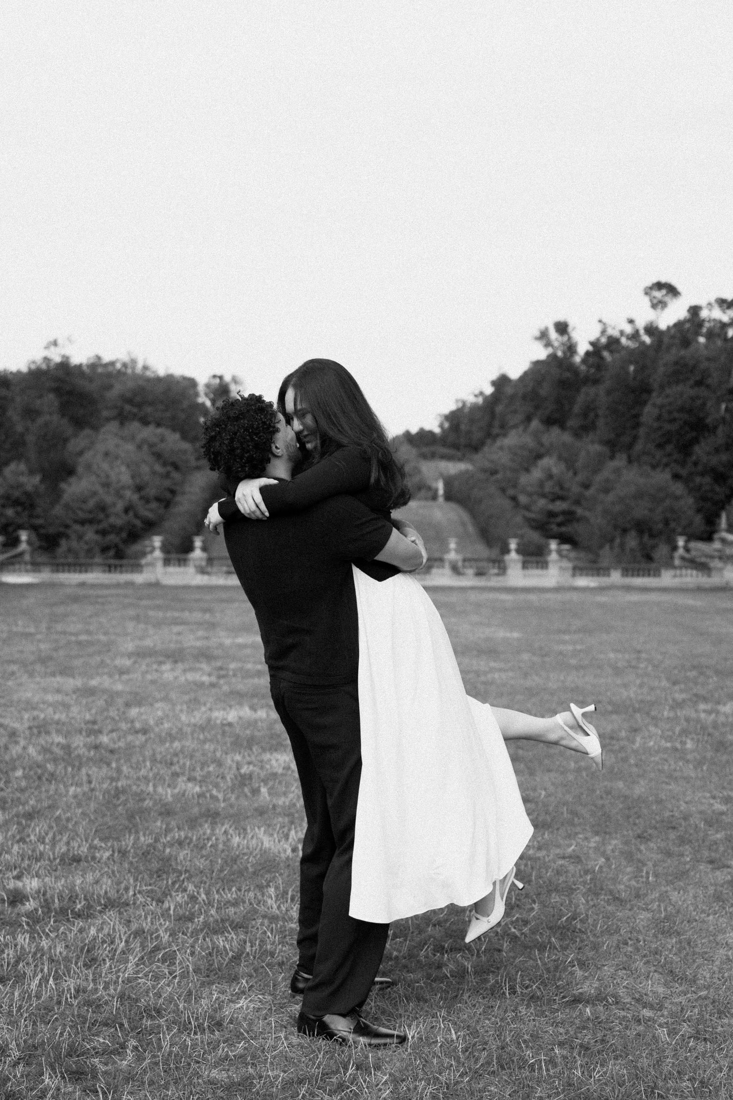 A romantic embrace captured in black and white on an open field.