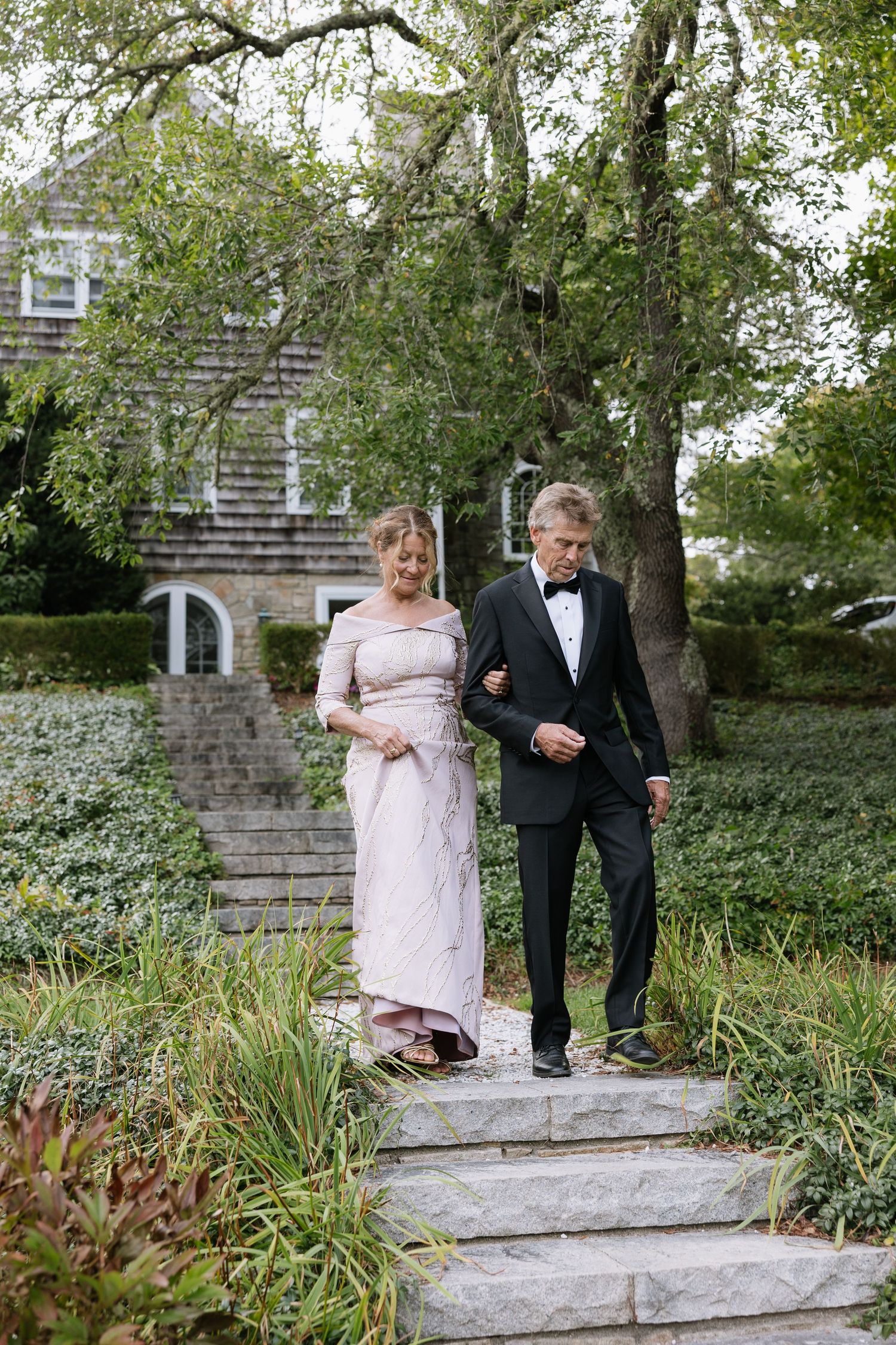 Couple walking down stone garden steps surrounded by lush greenery.