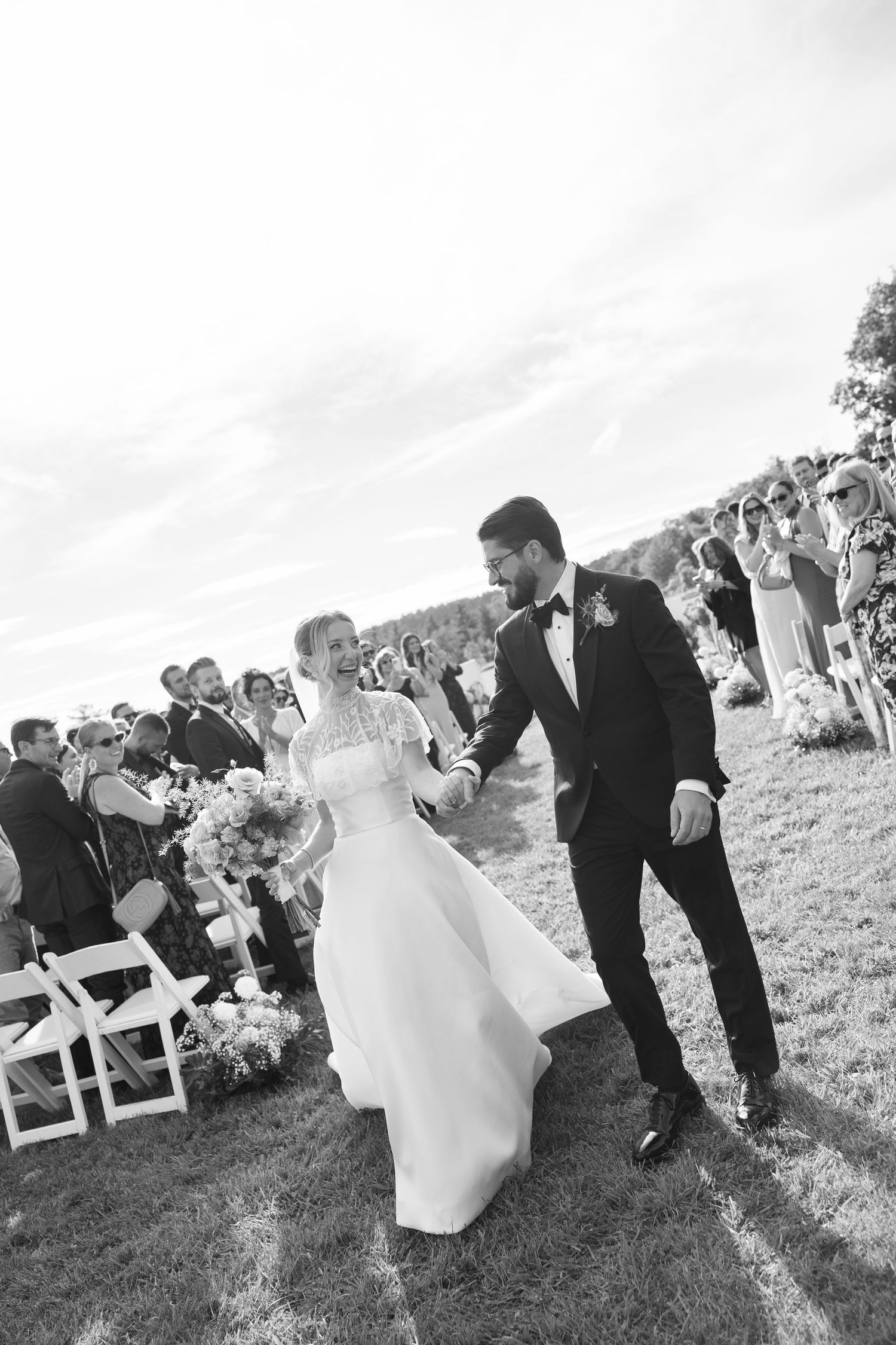 Bride and groom walk down the aisle at outdoor wedding ceremony in black and white photo.