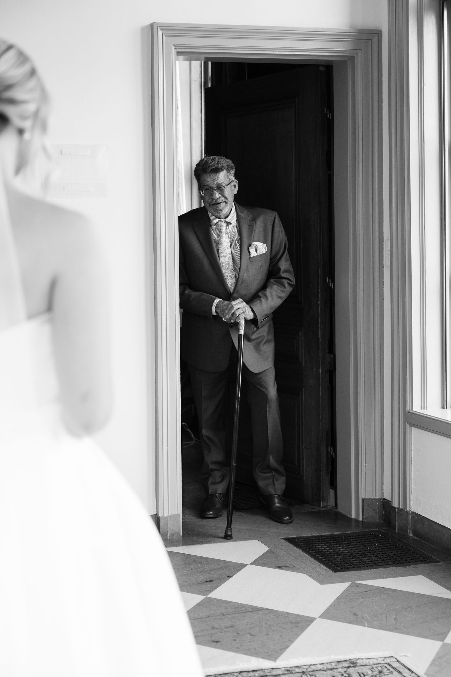 Dramatic black and white photo of a wedding first look moment in a doorway.