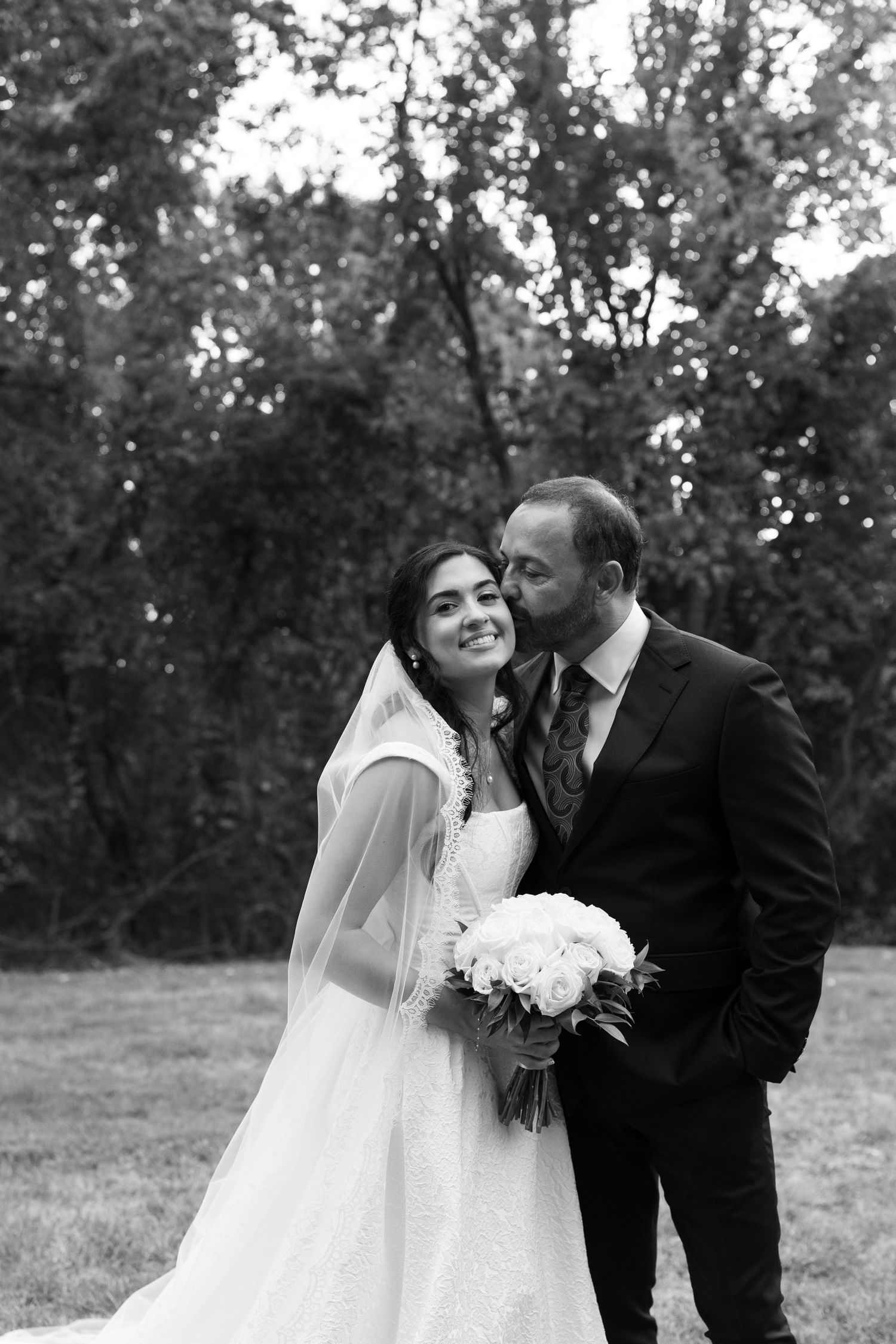 Romantic outdoor wedding portraits captured in natural lighting among trees.