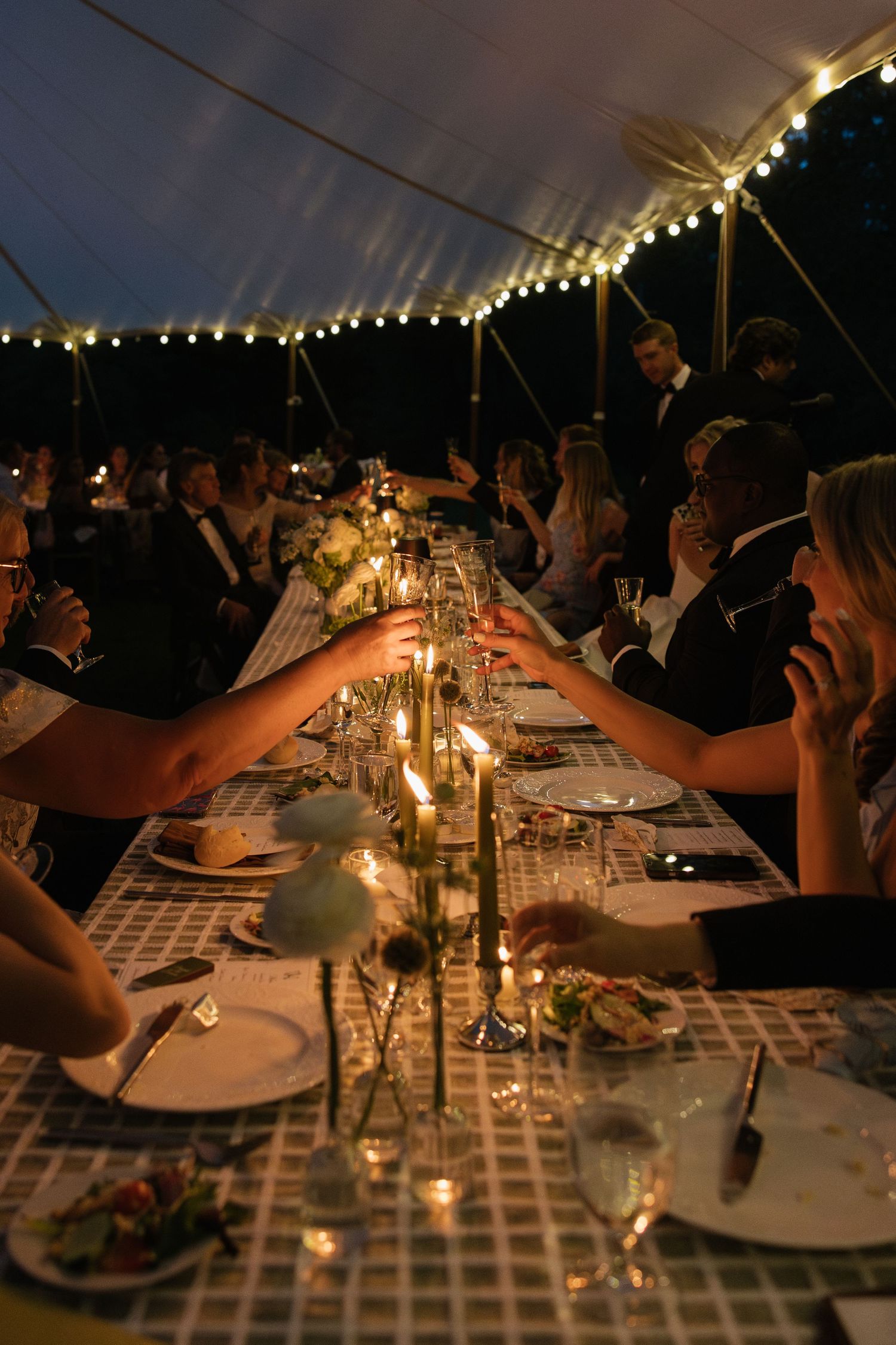 Elegant table settings with candlelight and glassware at an evening wedding reception.