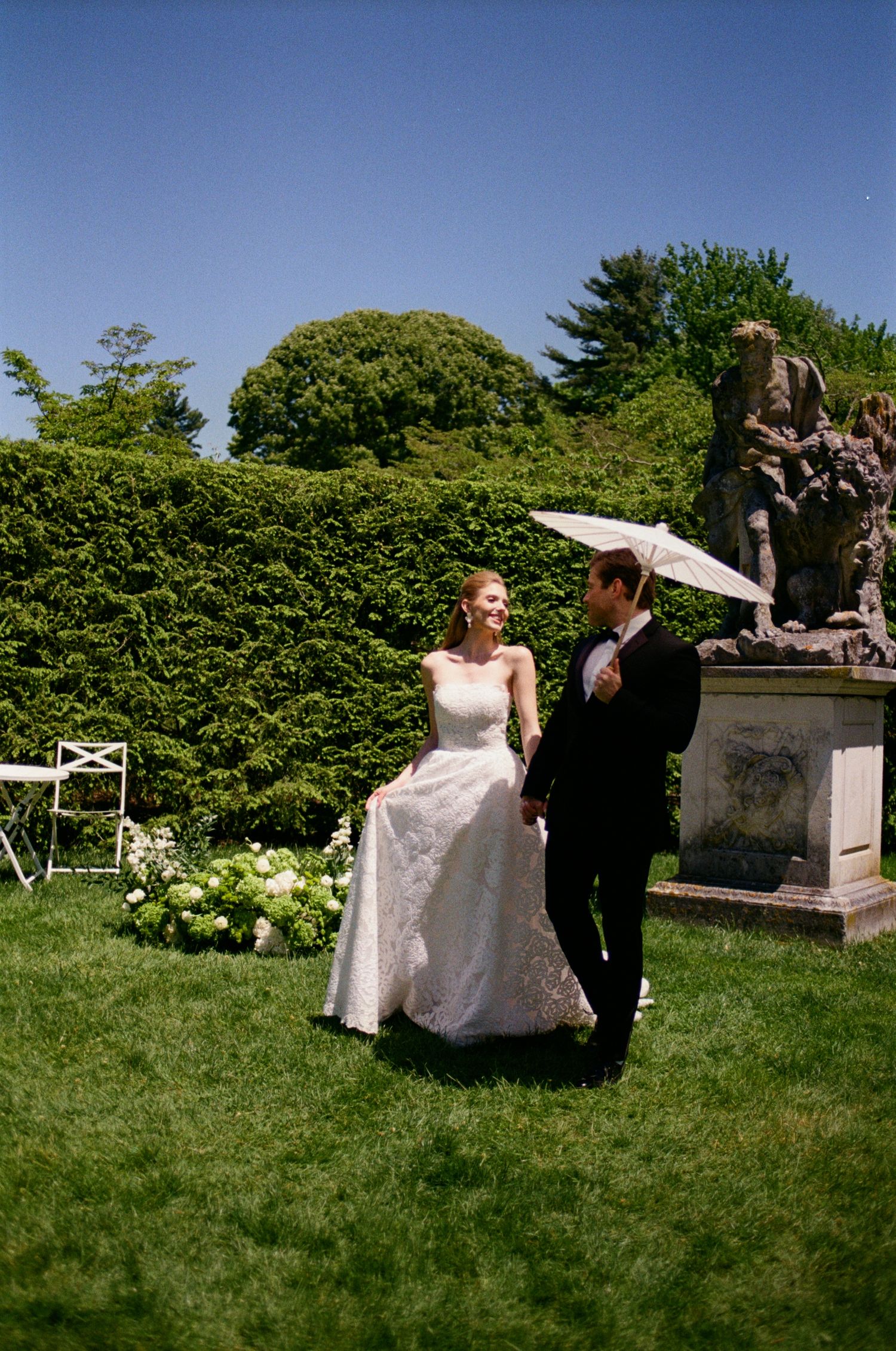 Romantic wedding photoshoot in a garden with decorative stone elements.