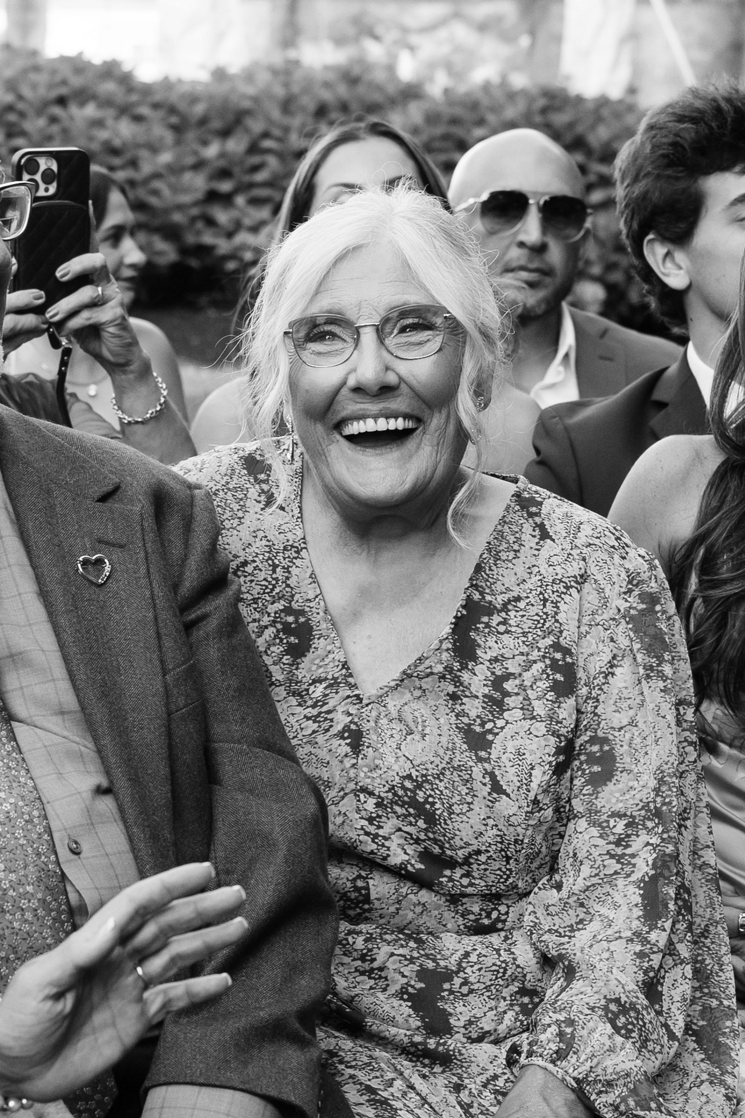 Black and white photo of wedding guests laughing and enjoying the celebration.
