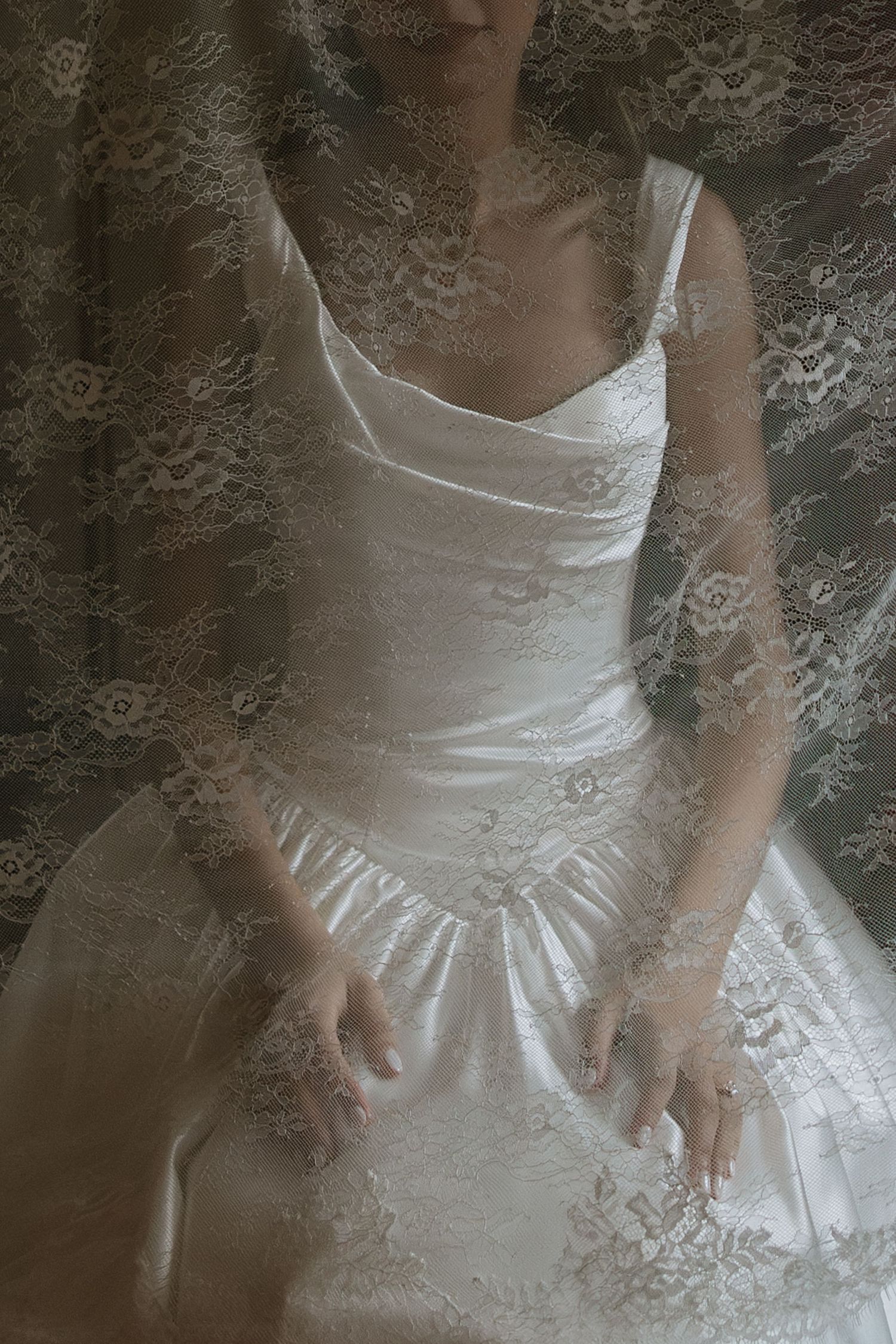 Bride in white satin wedding dress with lace veil overlay, elegant ball gown silhouette with sweetheart neckline.