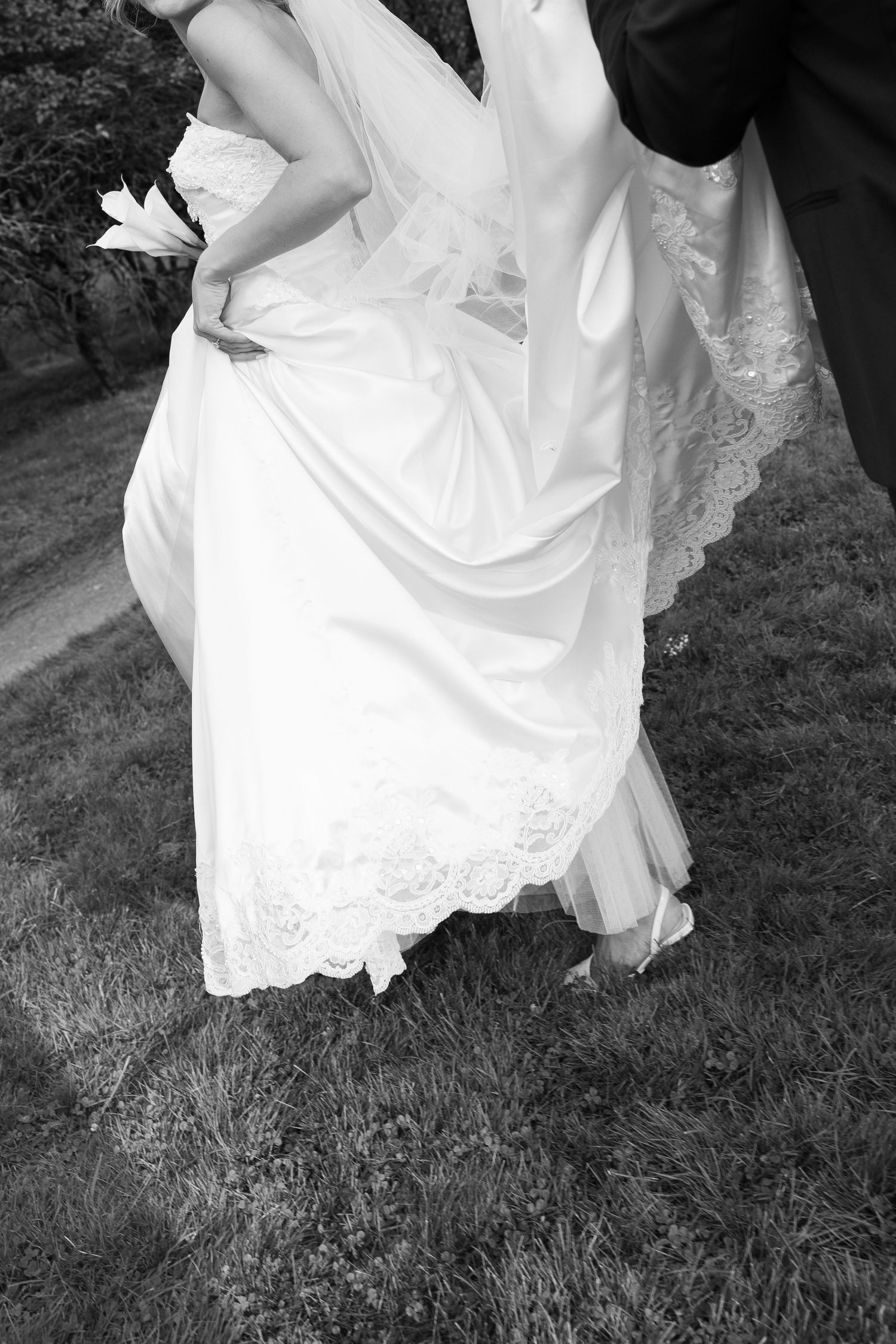 Black and white detail shots of wedding dress hem flowing over grass.