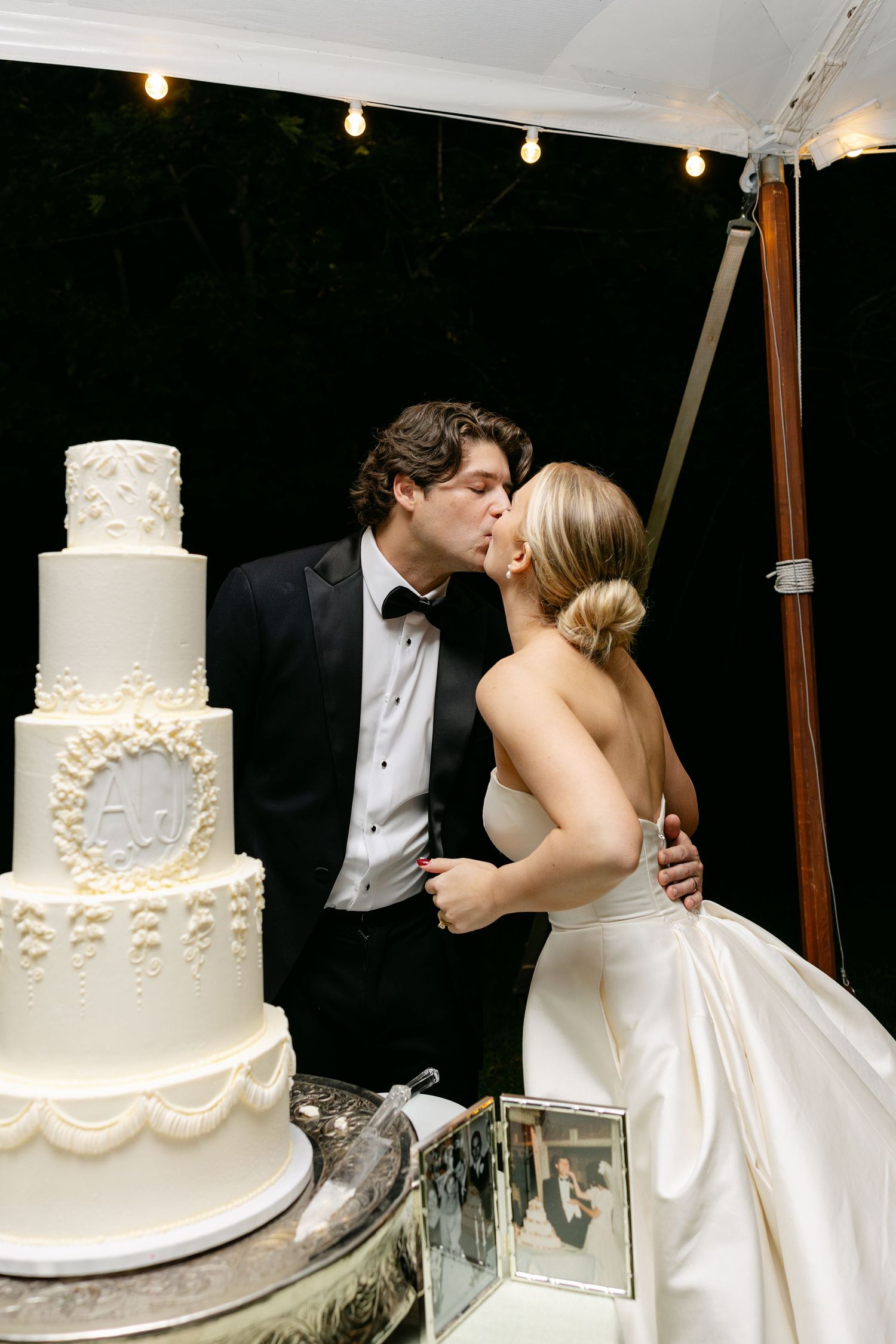 Classic white tiered wedding cake with delicate floral details displayed at reception.