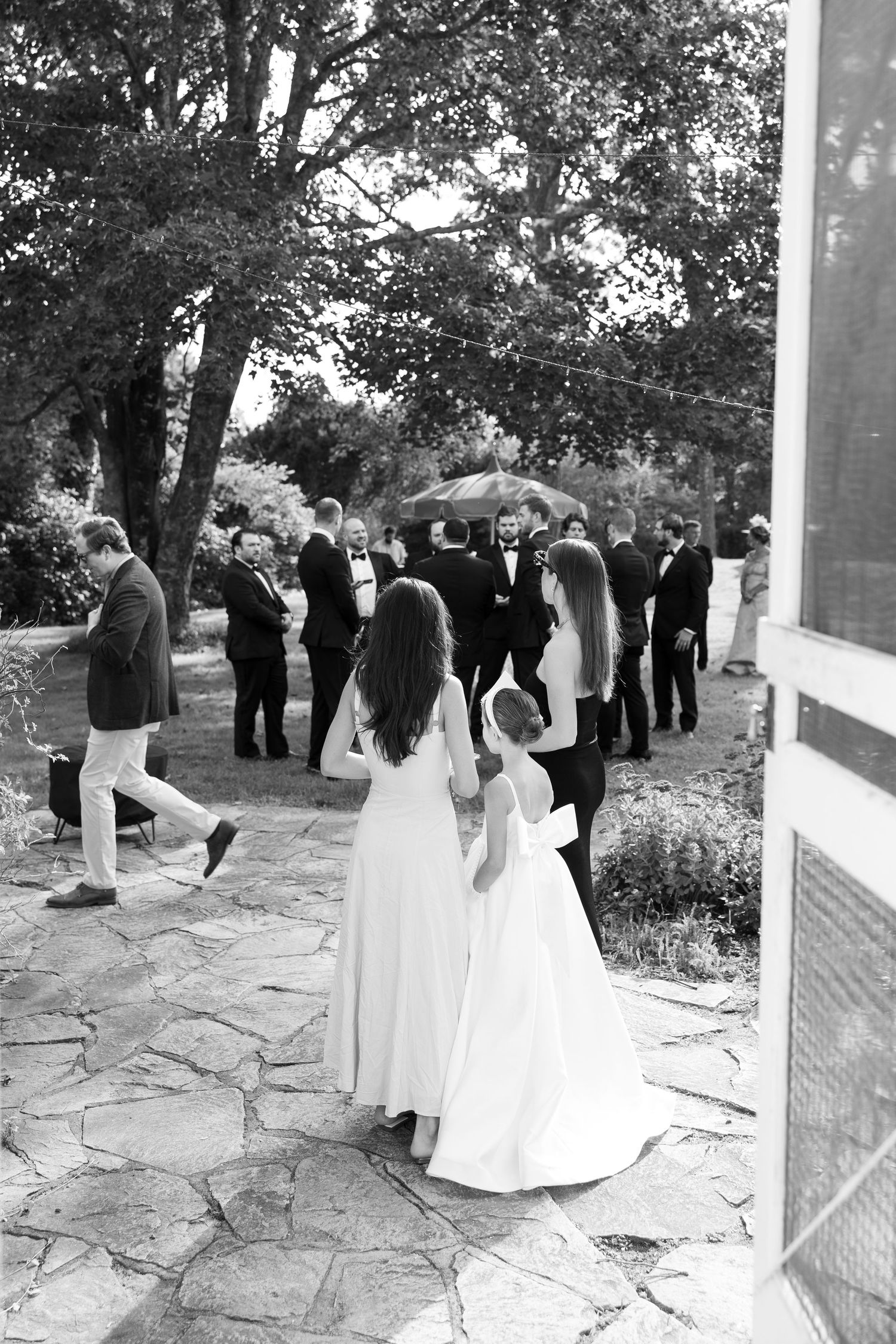 Black and white photo of wedding guests gathered on a stone patio during an outdoor ceremony.