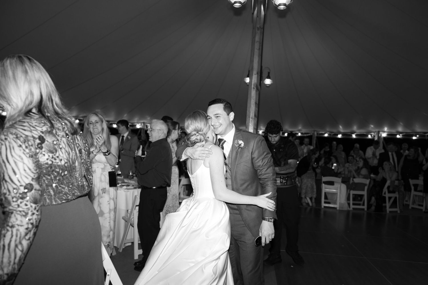 Bride and groom share a romantic first dance under a large tent at their wedding reception.