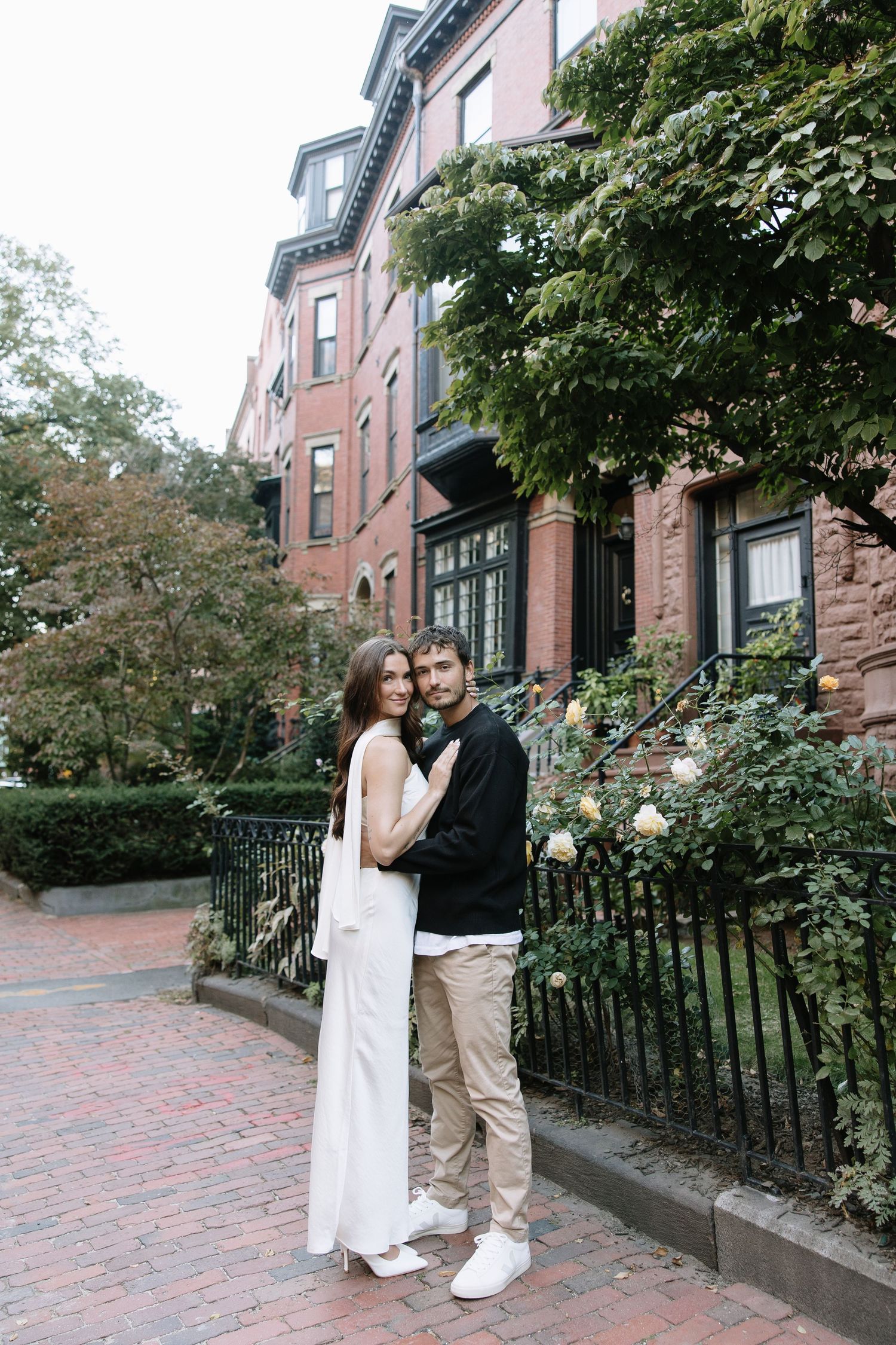 Romantic photo sequence in front of historic brownstone buildings with garden.