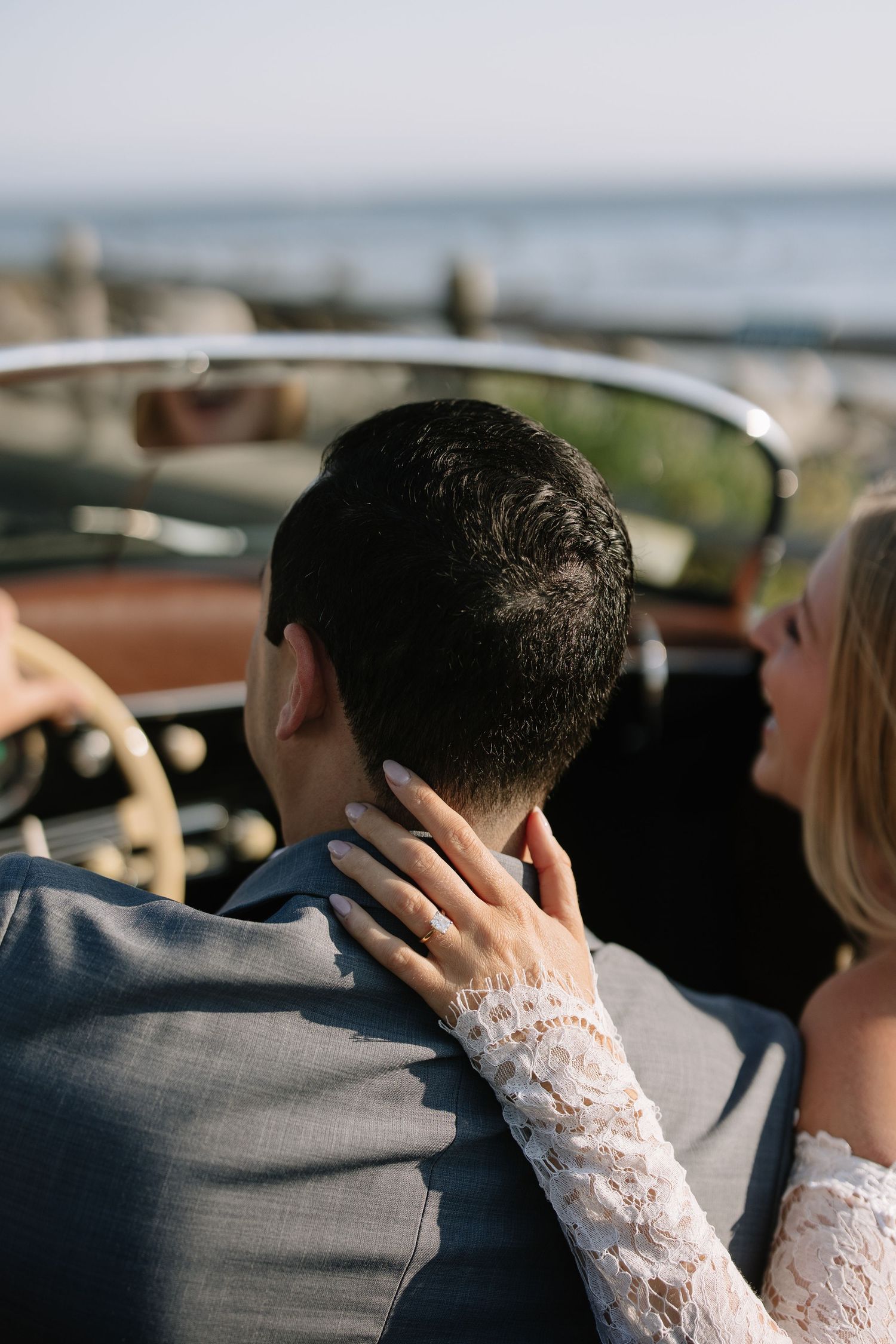 Romantic moment captured in a classic car with lace sleeves visible.