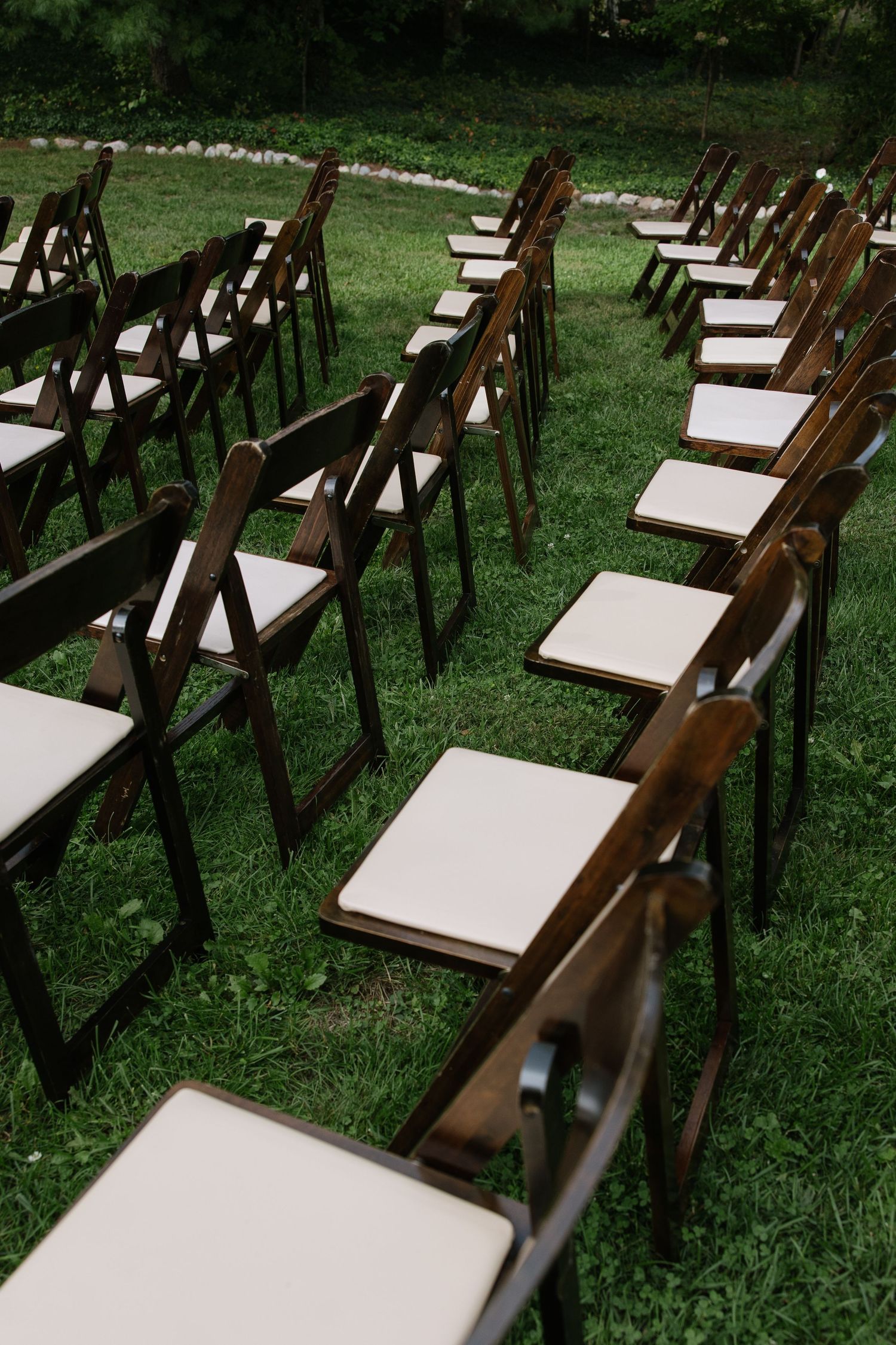 Rows of wooden folding chairs set up on grass for an outdoor wedding ceremony.